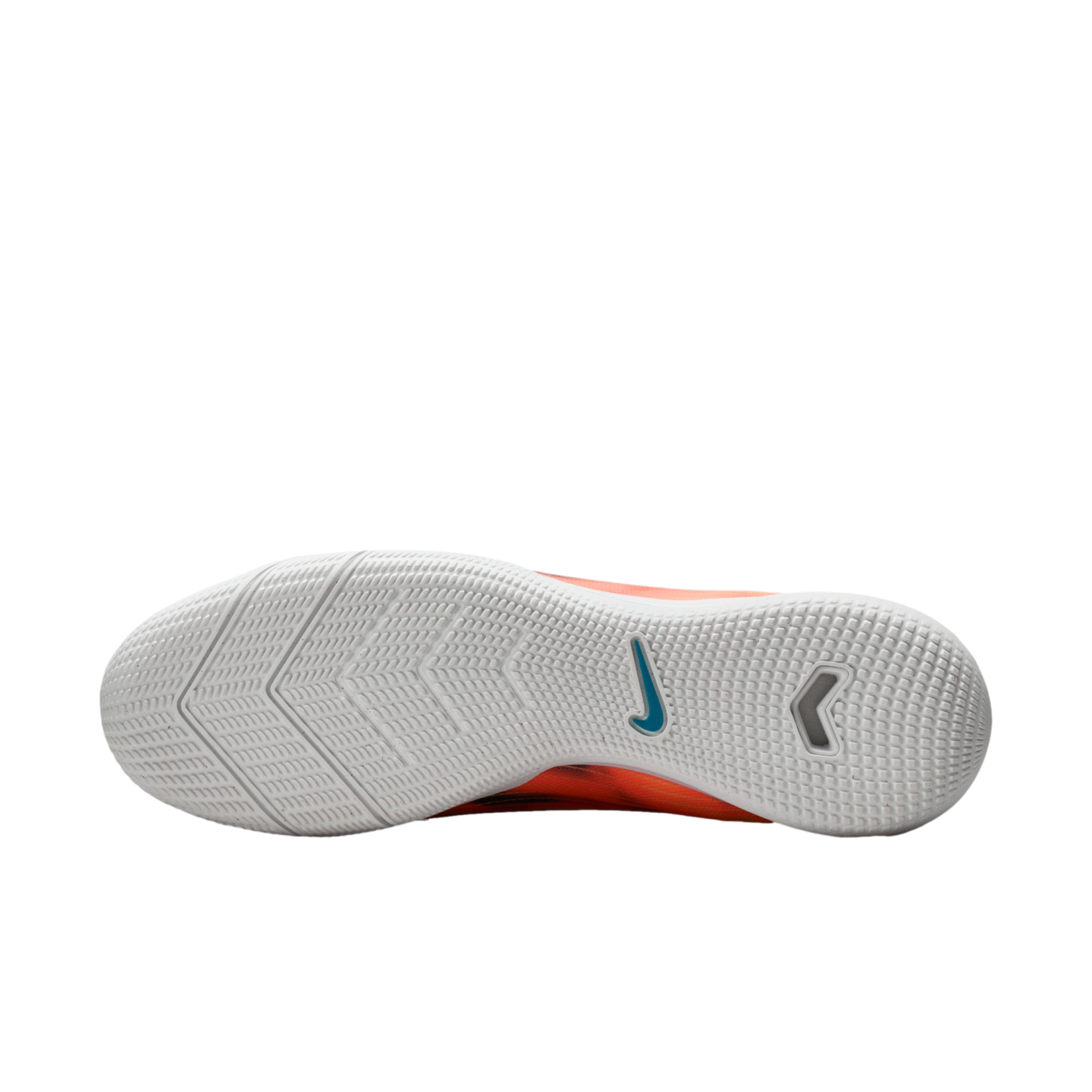 White textured rubber sole of an orange Nike indoor soccer shoe with a blue swoosh logo, shown against a black background.