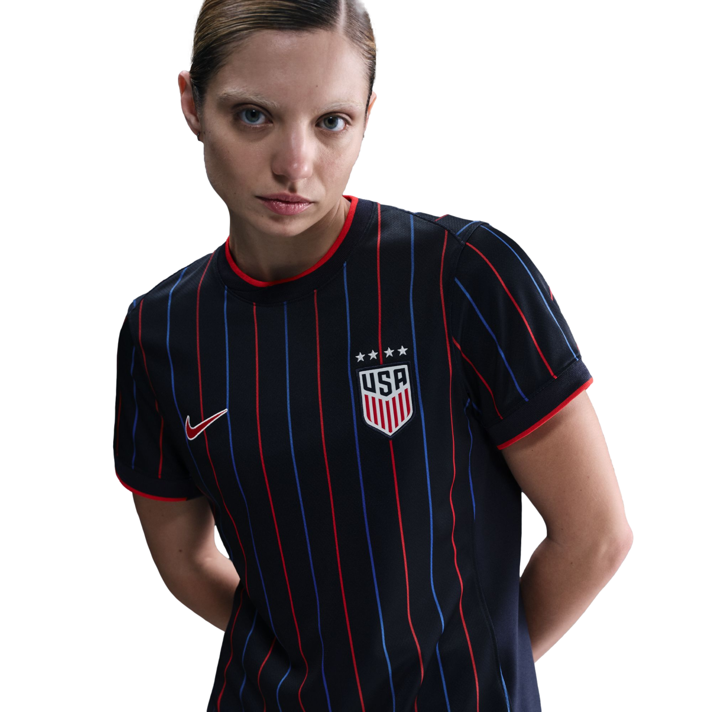 Woman wearing a black USA soccer jersey with red and blue pinstripes and four stars above the crest, posing against a white background.