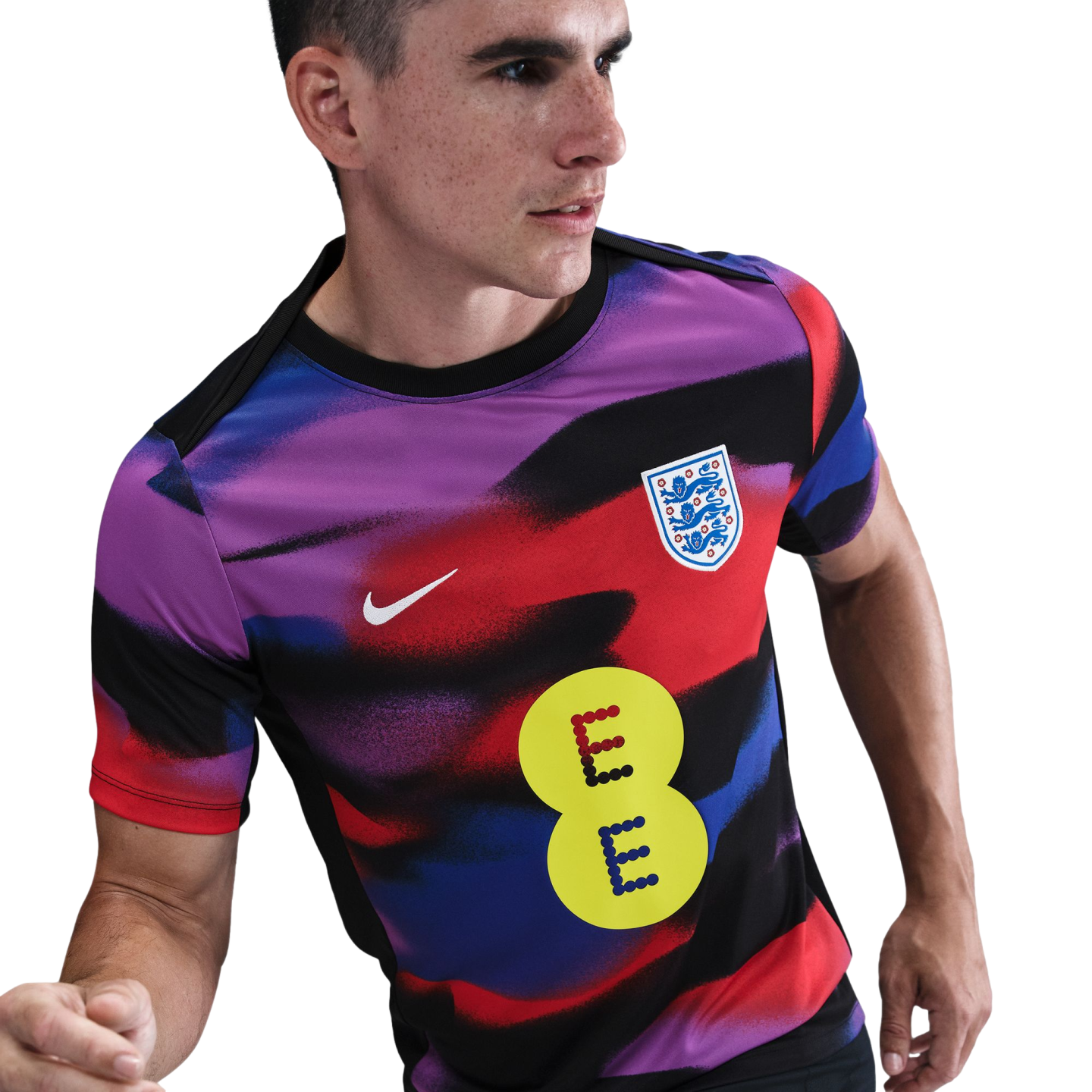 A man wears a vibrant England football training jersey featuring a purple, red, and blue wavy pattern with a yellow EE logo on the front.