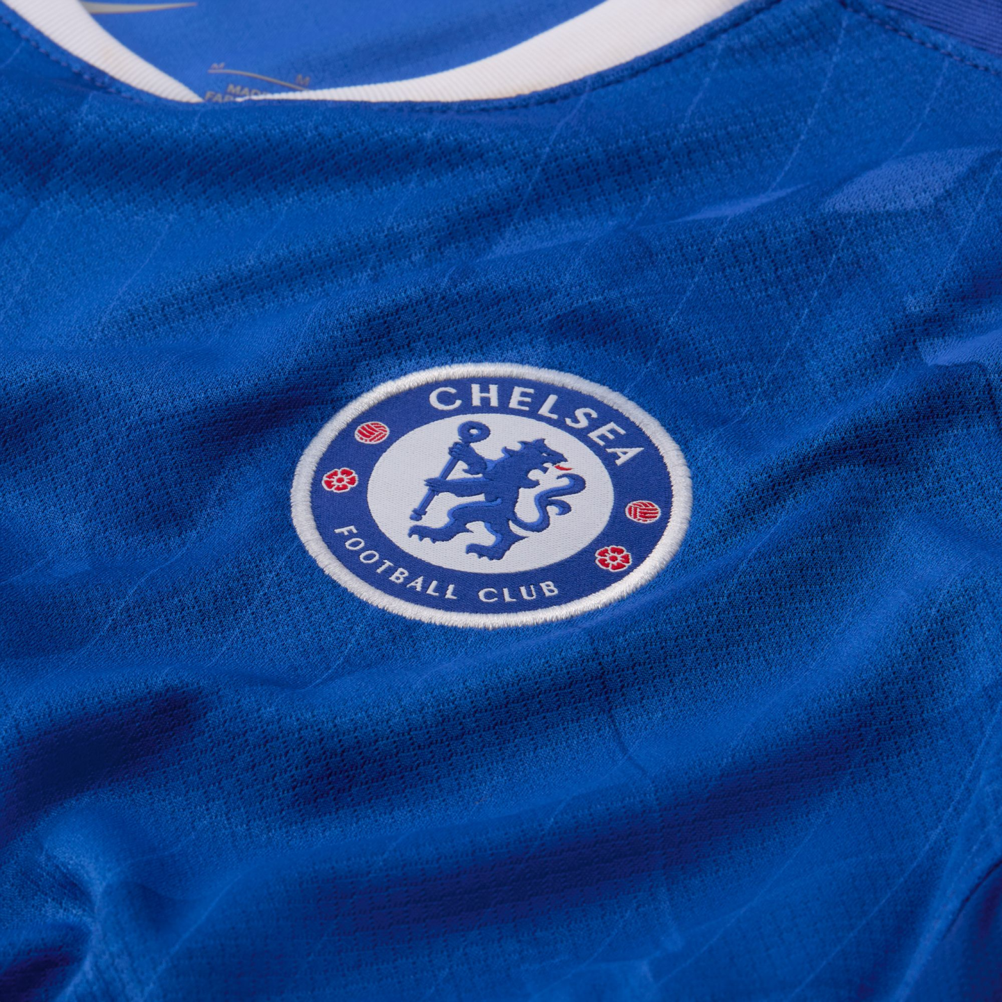 Close-up of the Chelsea Football Club crest embroidered on a textured blue soccer jersey.