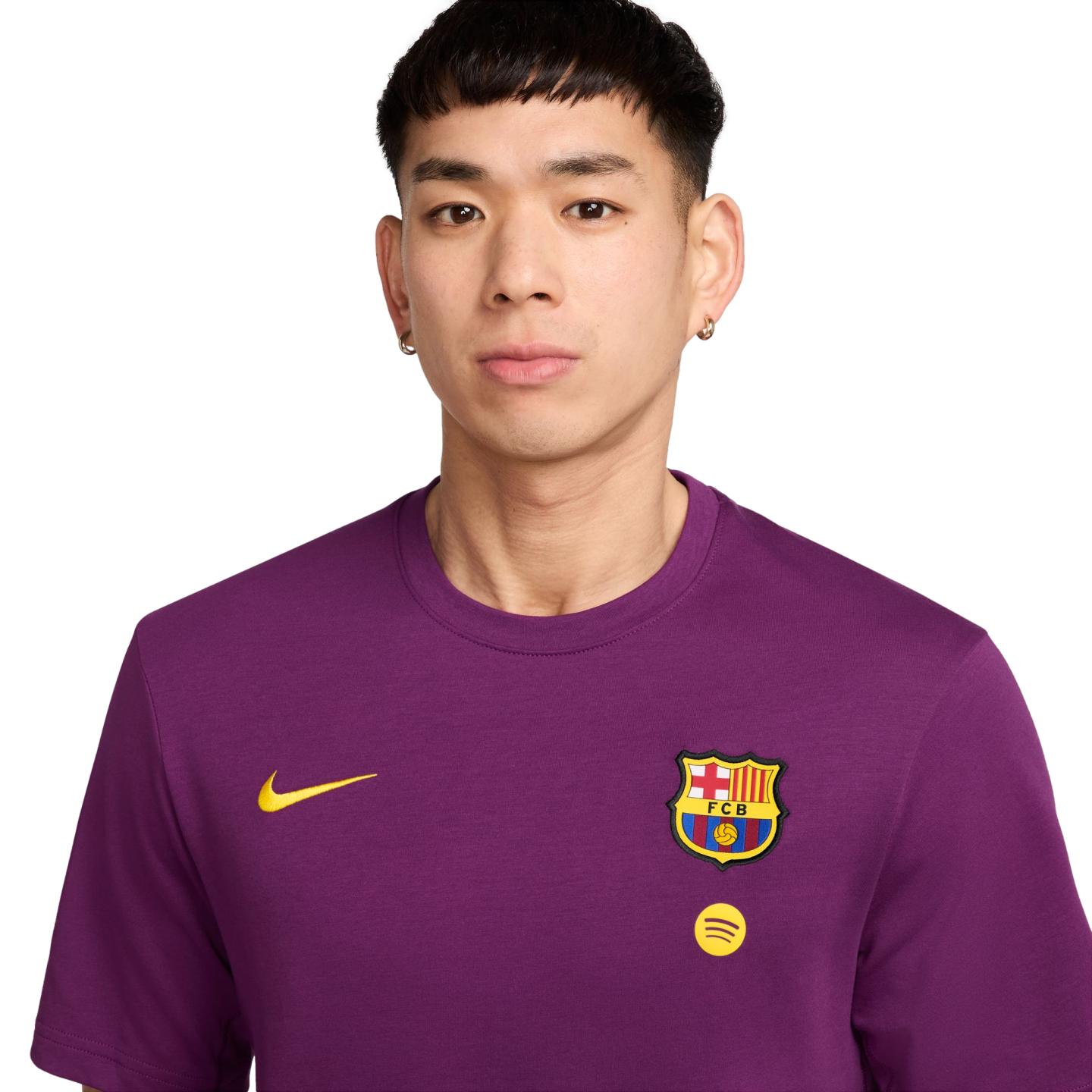 Headshot of a person with short dark hair wearing a purple Nike FC Barcelona t-shirt with the team crest and a Spotify logo, against a solid black background.