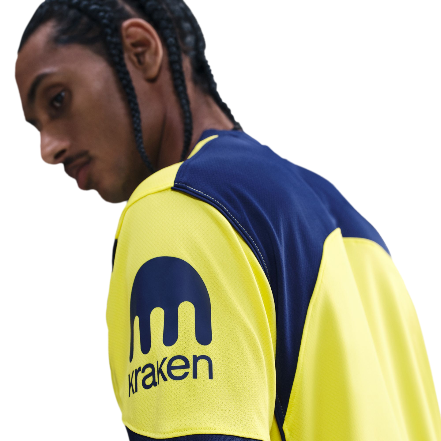 Profile of a person with braided hair wearing a yellow and blue jersey featuring the Kraken logo on the sleeve.