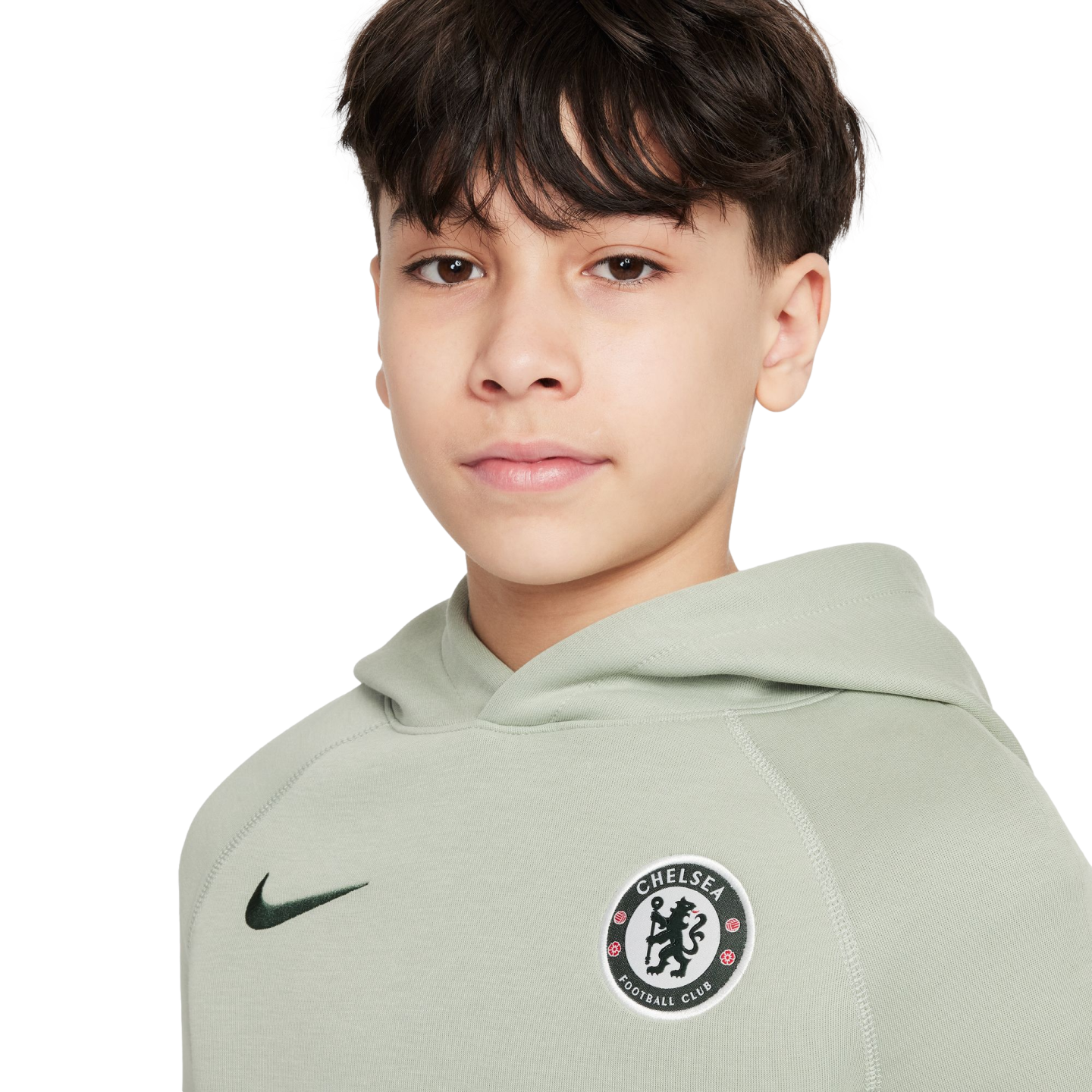 Young person with dark hair wearing a sage green Nike Chelsea Football Club hoodie against a plain white background.