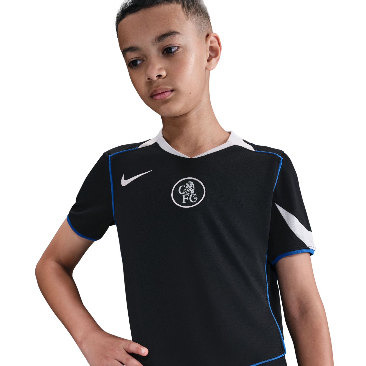A boy wears a black Nike Chelsea FC soccer jersey with blue trim and a white crest, looking down against a plain black background.