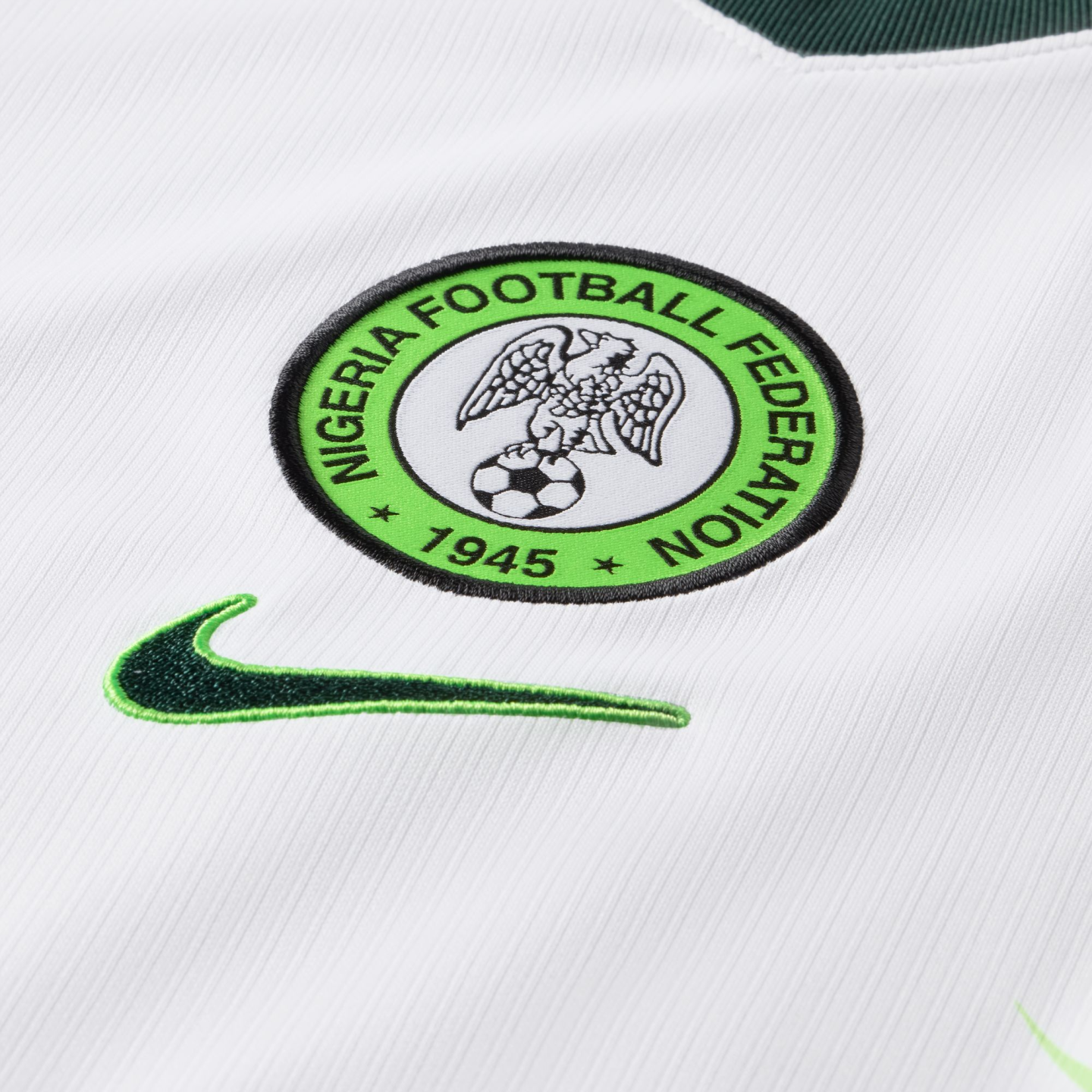 Close-up of a white Nigeria football jersey featuring the Nigeria Football Federation embroidered crest and a green Nike swoosh.
