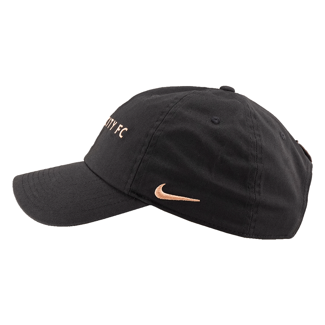 Side profile of a black baseball cap with rose-gold embroidery, featuring a Nike swoosh on the side and "CITY FC" on the front crown.