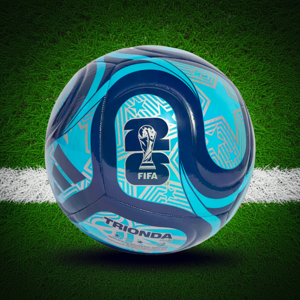 A blue and silver patterned soccer ball with FIFA World Cup 2026 and Adidas branding sits on a green grass field near a white line.