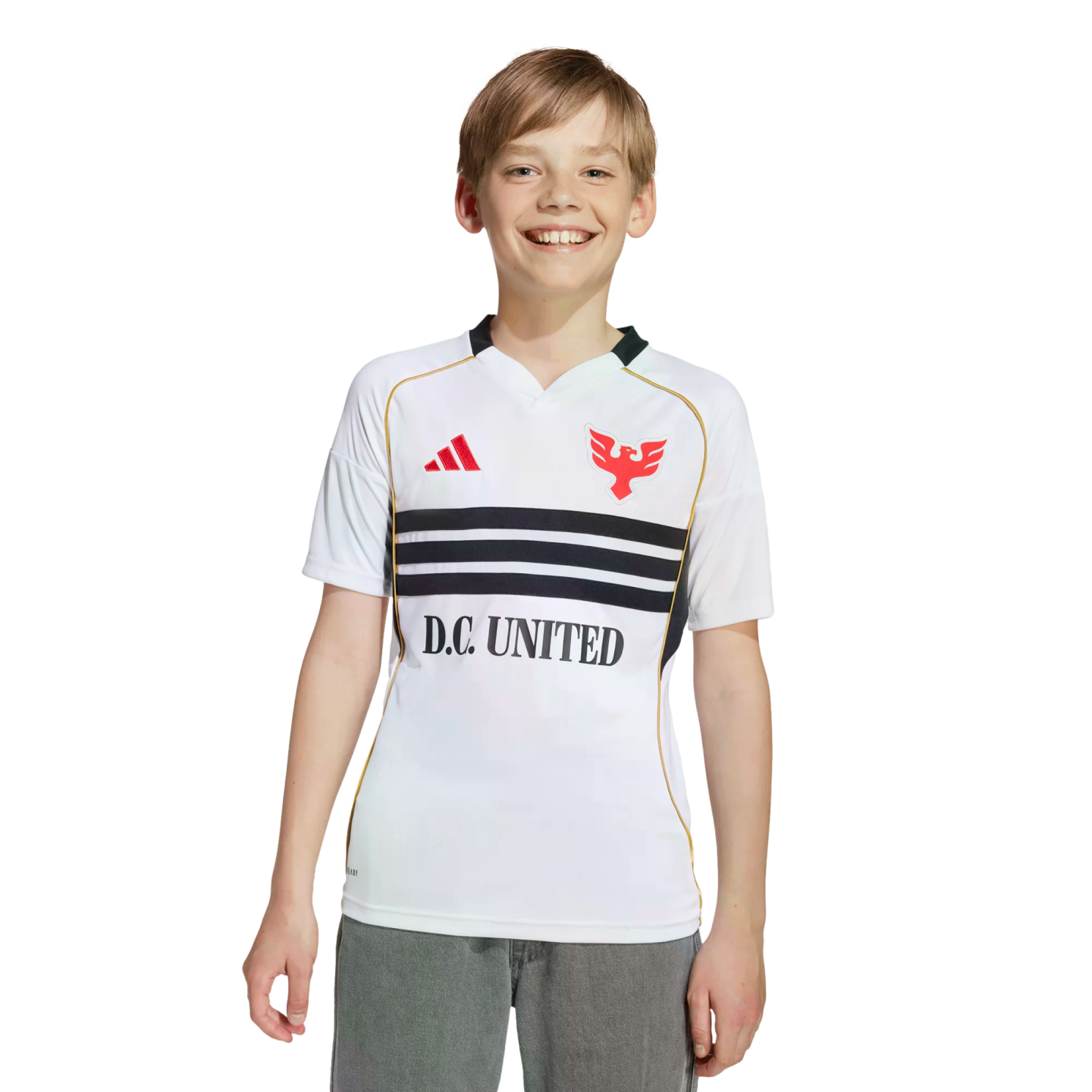 A smiling young boy in a white D.C. United soccer jersey and grey pants against a black background.