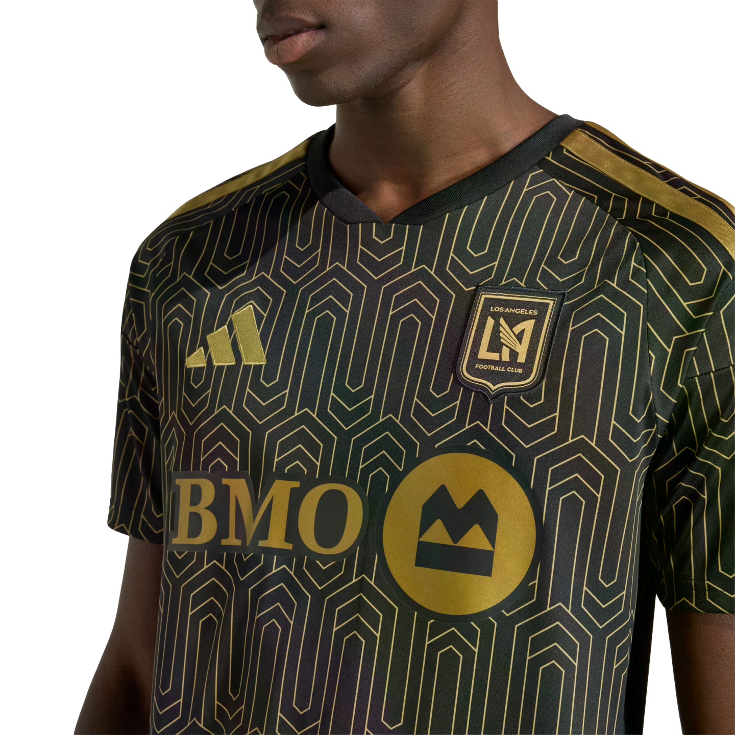 A person wearing a black and gold LAFC soccer jersey with an intricate geometric pattern. Features the gold Adidas logo, team crest, and BMO sponsor logo.