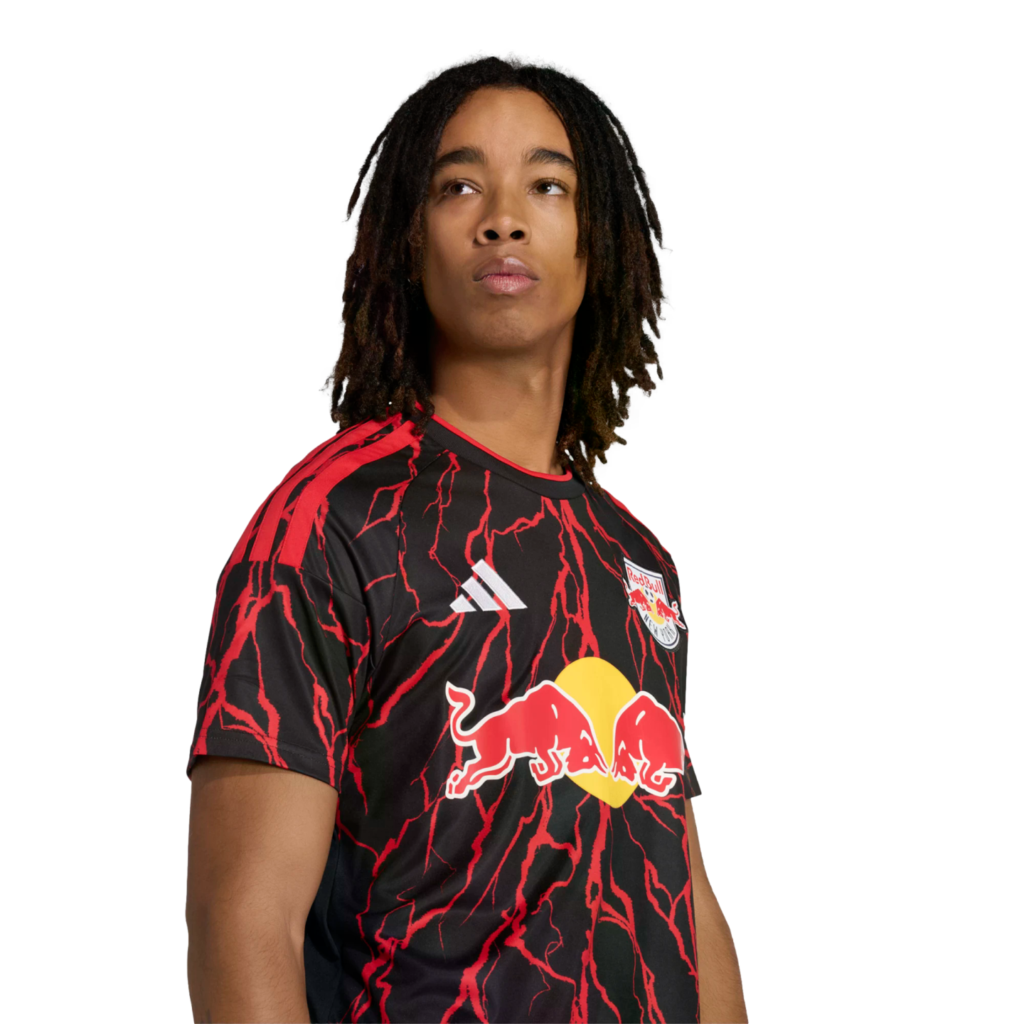 A person with long dreadlocks wearing a black and red lightning-patterned New York Red Bulls soccer jersey against a black background.