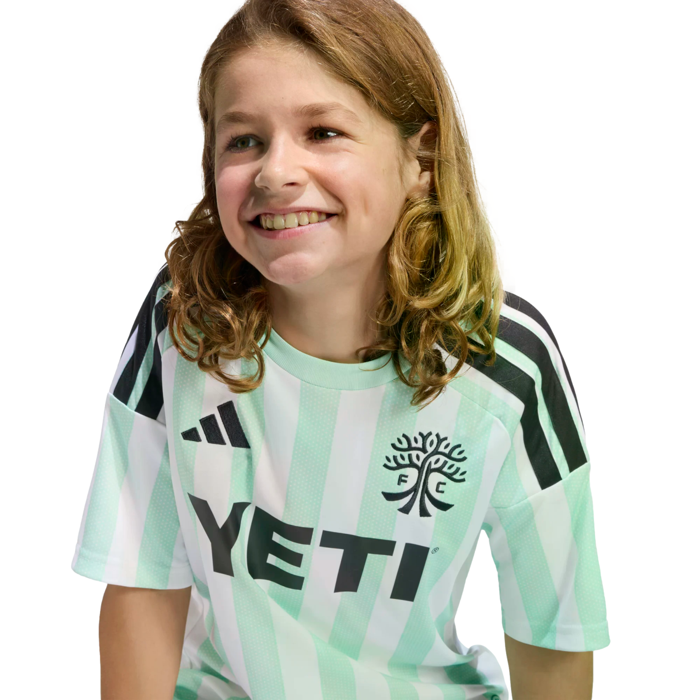 A smiling child with long, wavy brown hair wearing a mint green and white striped Austin FC jersey with a black Yeti logo, set against a solid black background.