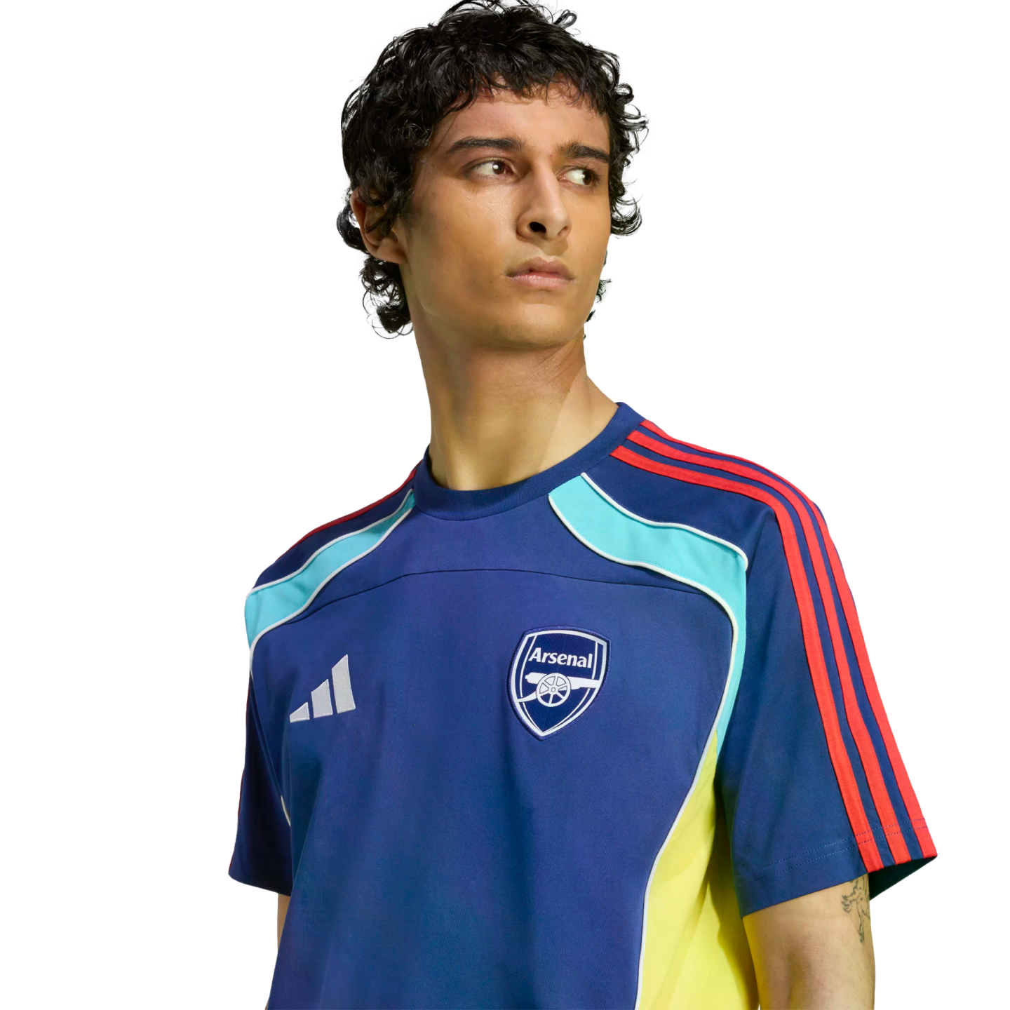 Man wearing a blue Adidas Arsenal training jersey with red, light blue, and yellow accents, looking to the side against a black background.