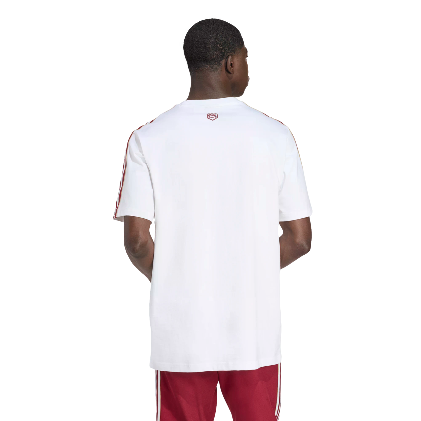 Rear view of a man wearing a white t-shirt with red shoulder stripes and red shorts against a black background.