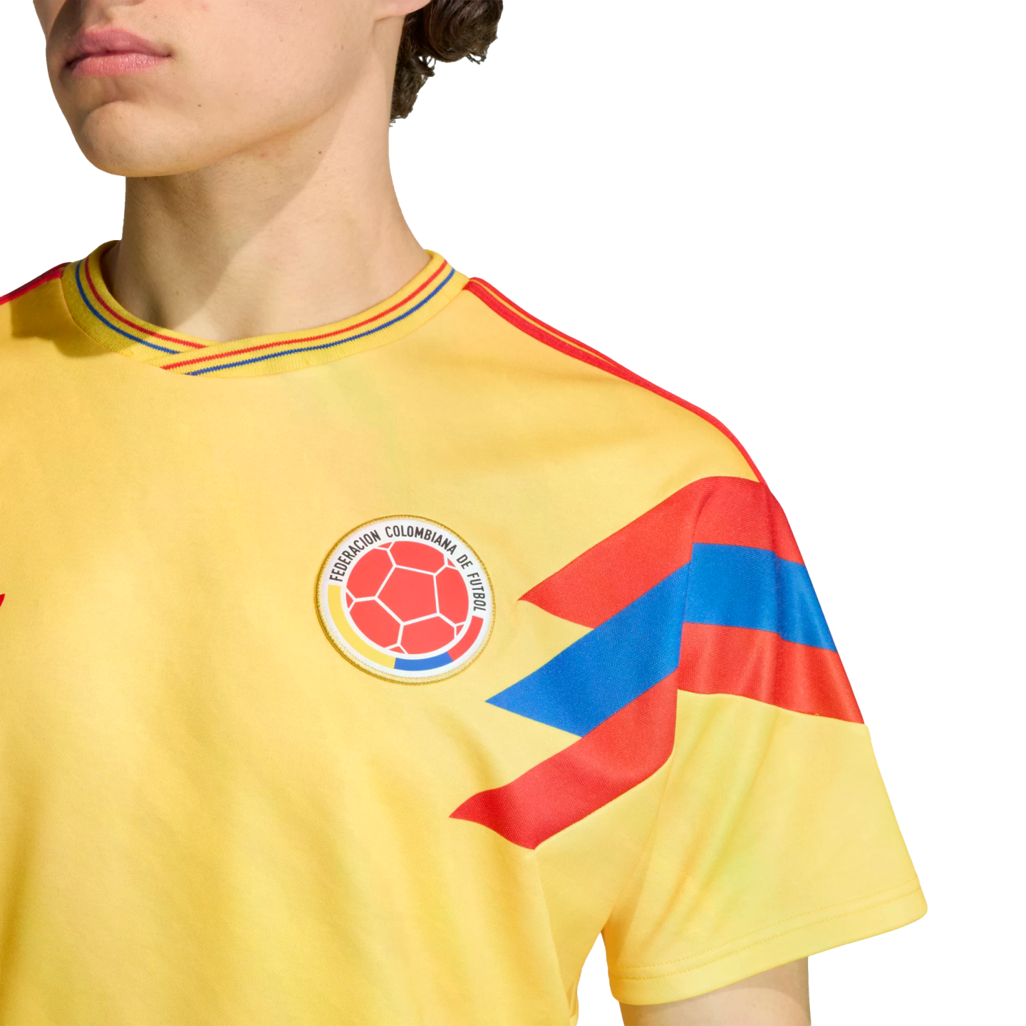 Close-up of a person wearing a yellow Colombia national football team jersey with the team crest and red and blue patterns on the sleeve and collar.