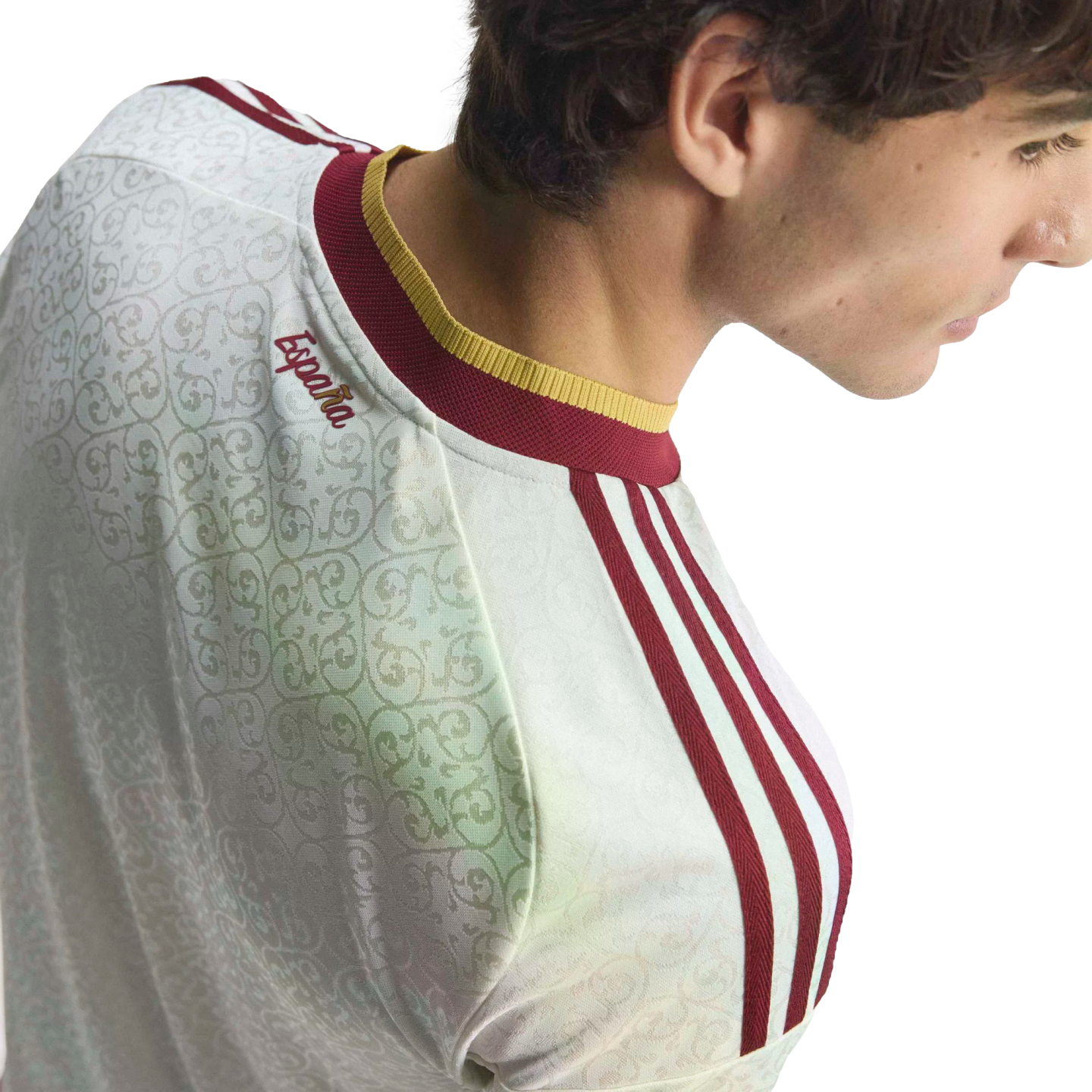 Profile of a man wearing a white Spain football jersey with maroon and gold trim and "España" embroidered on the back neck.