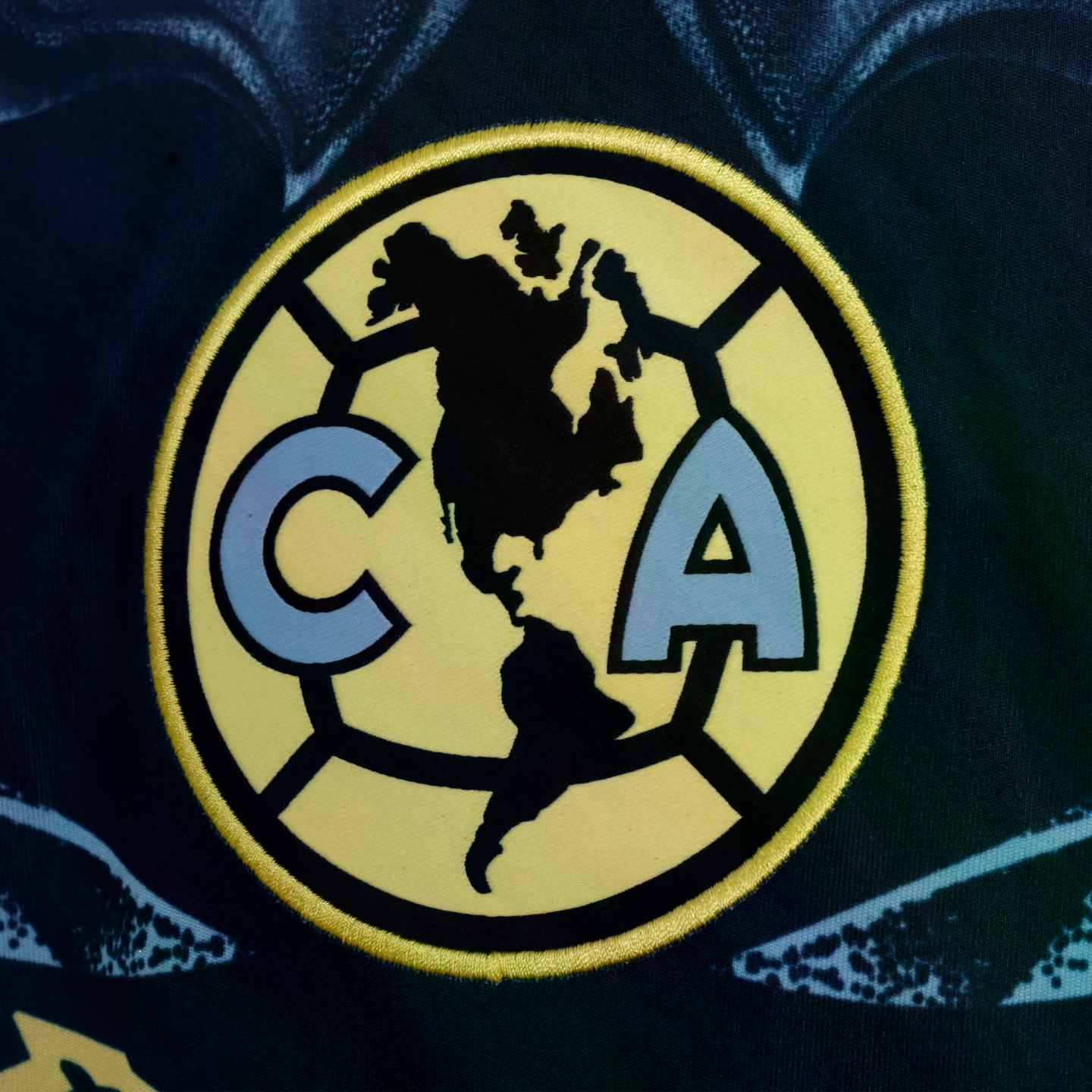 Emblem of Club América, featuring a black map of the Americas between light blue letters "C" and "A" on a yellow circle.
