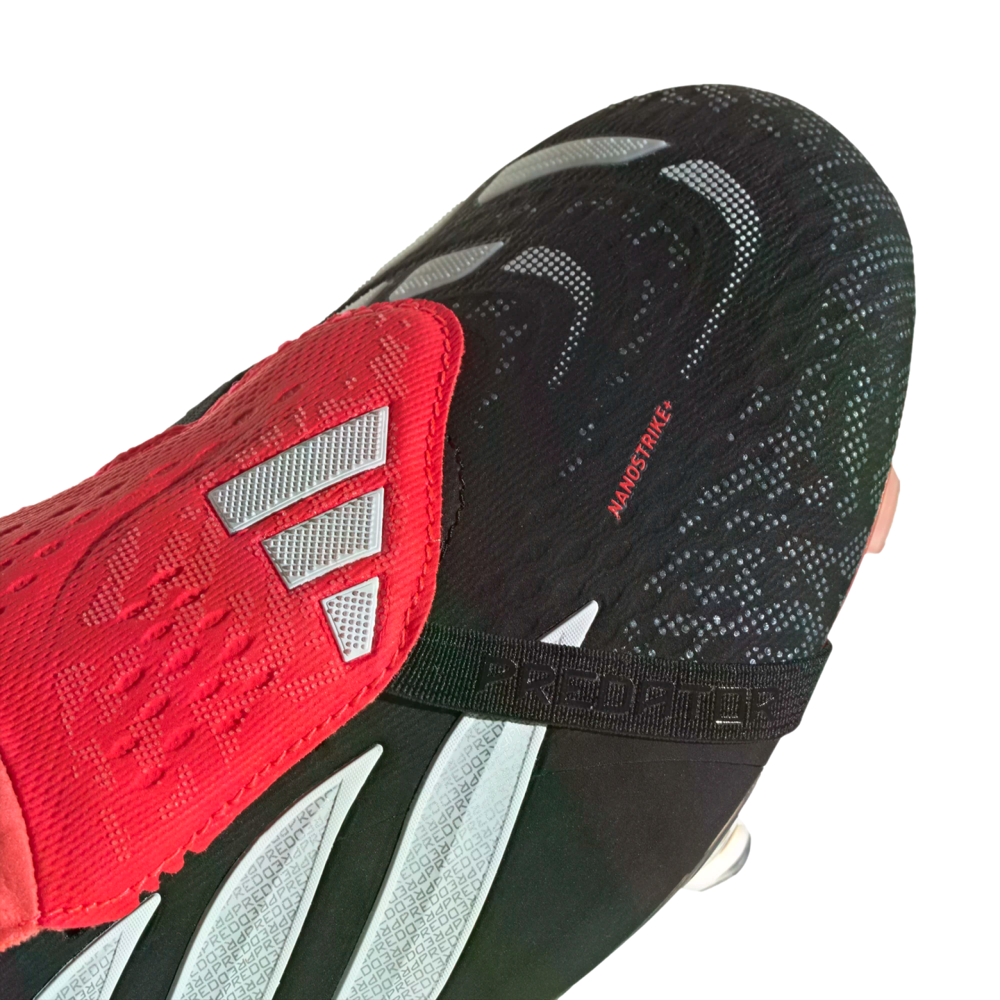 Close-up of a black and red Adidas Predator soccer cleat featuring a textured "NANOSTRIKE+" upper, red fold-over tongue with silver stripes, and a black "PREDATOR" strap.