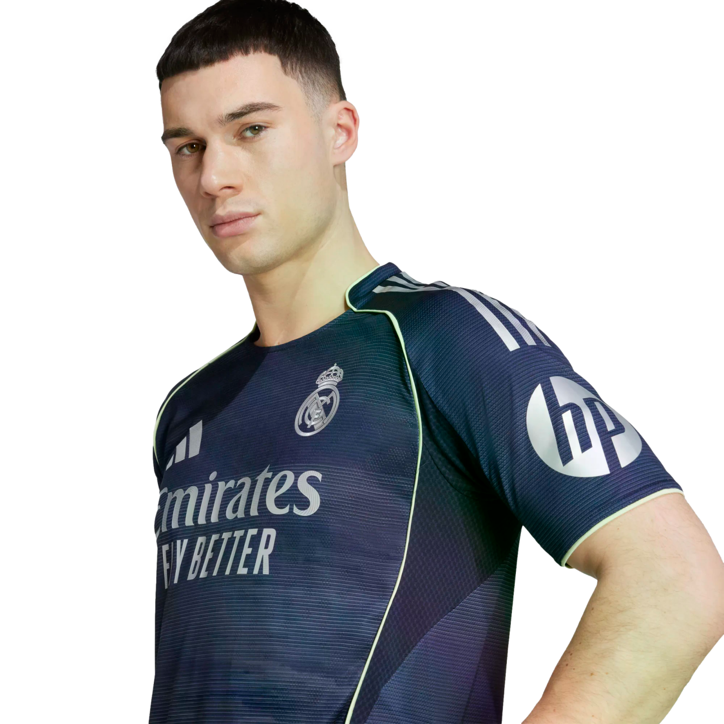 Young man wearing a navy Real Madrid training jersey with silver logos and neon green trim, posing against a white background.