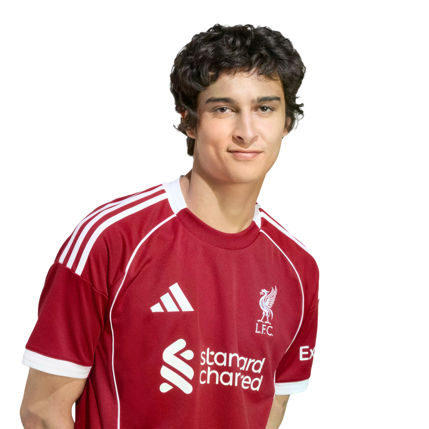 A young man with wavy dark hair wearing a red Liverpool F.C. soccer jersey against a solid black background.