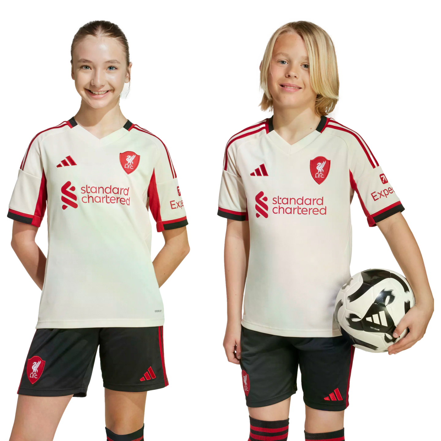 A girl and a boy wearing matching Liverpool FC jerseys and shorts smile against a black background. The boy holds a soccer ball.
