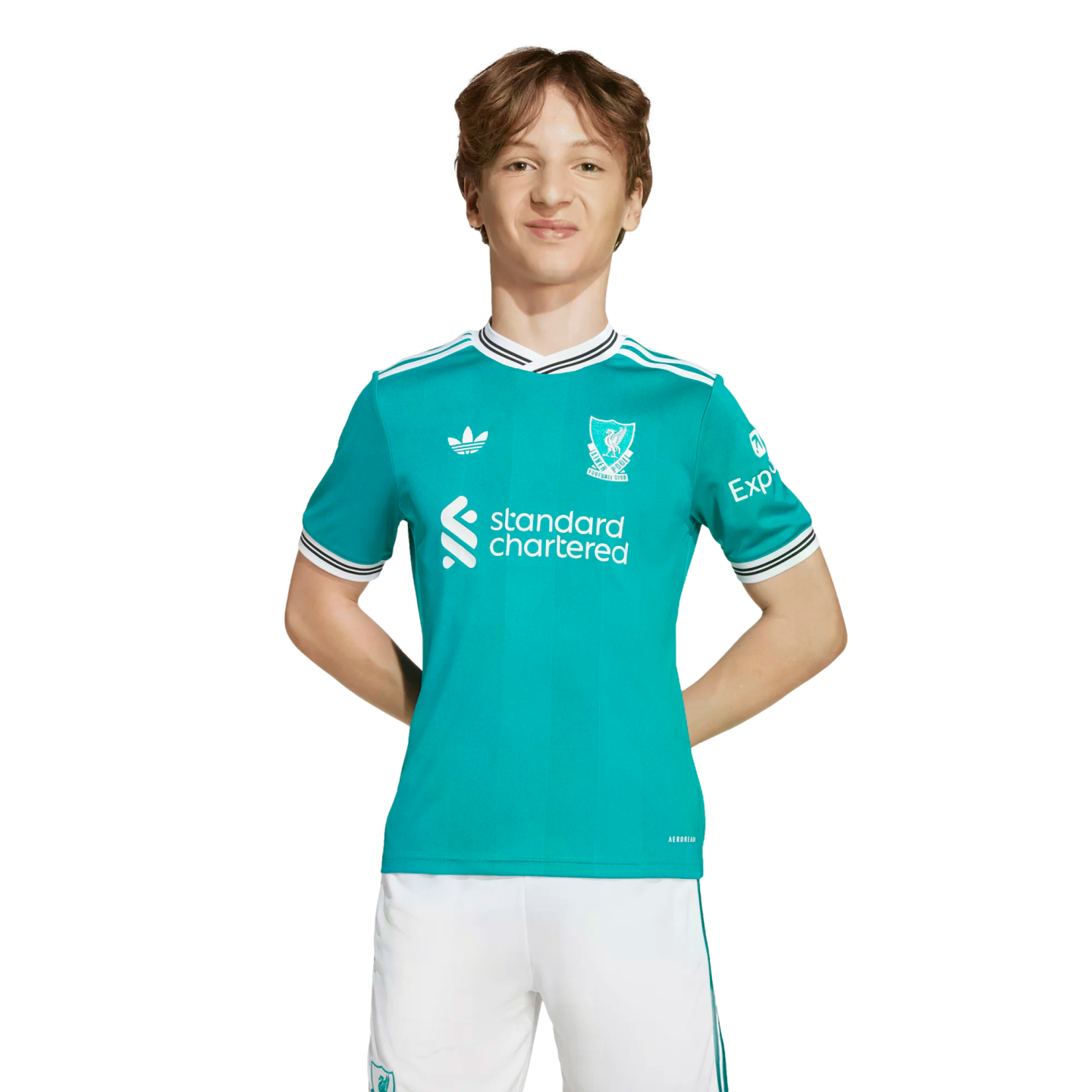 A young person with wavy brown hair wearing a teal Liverpool FC soccer jersey and white shorts, standing against a solid black background.