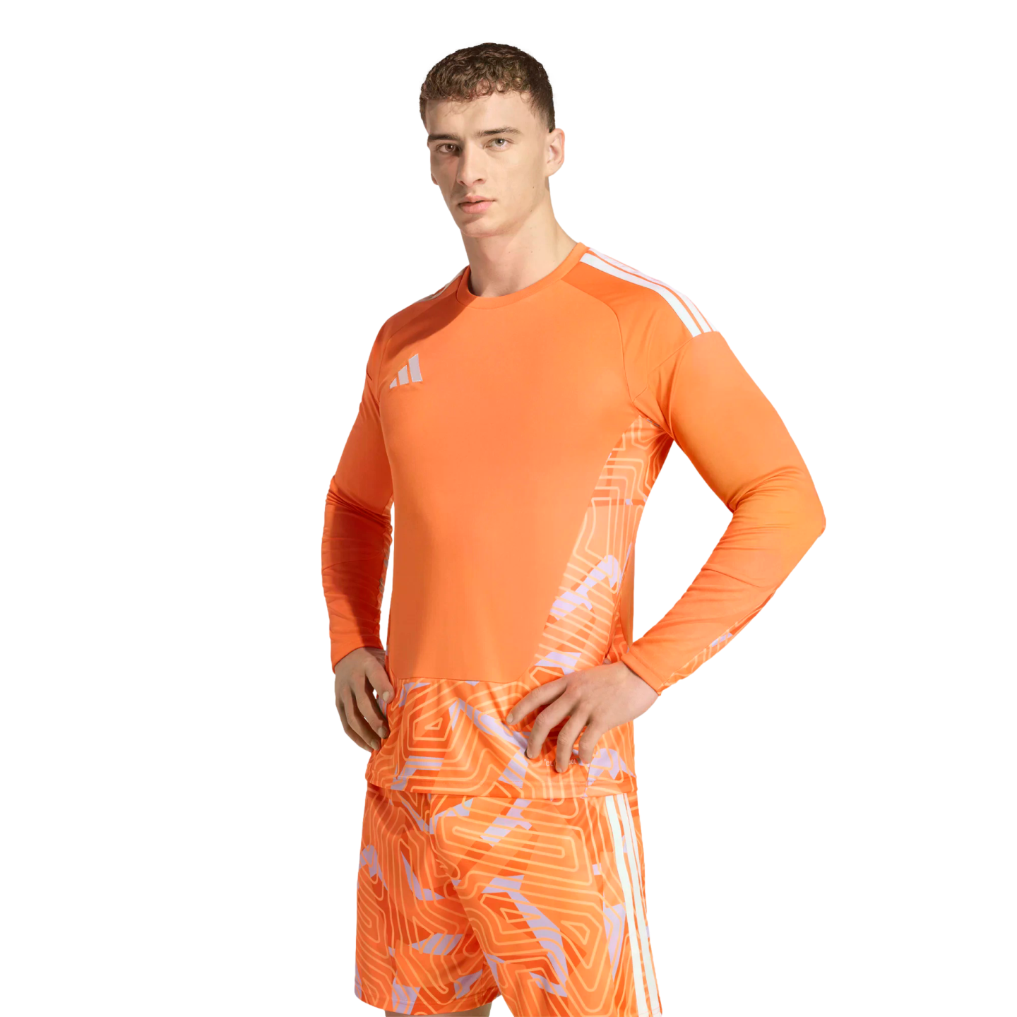 A man wearing a bright orange Adidas goalkeeper kit with geometric patterns on the jersey and shorts, posing against a solid black background.