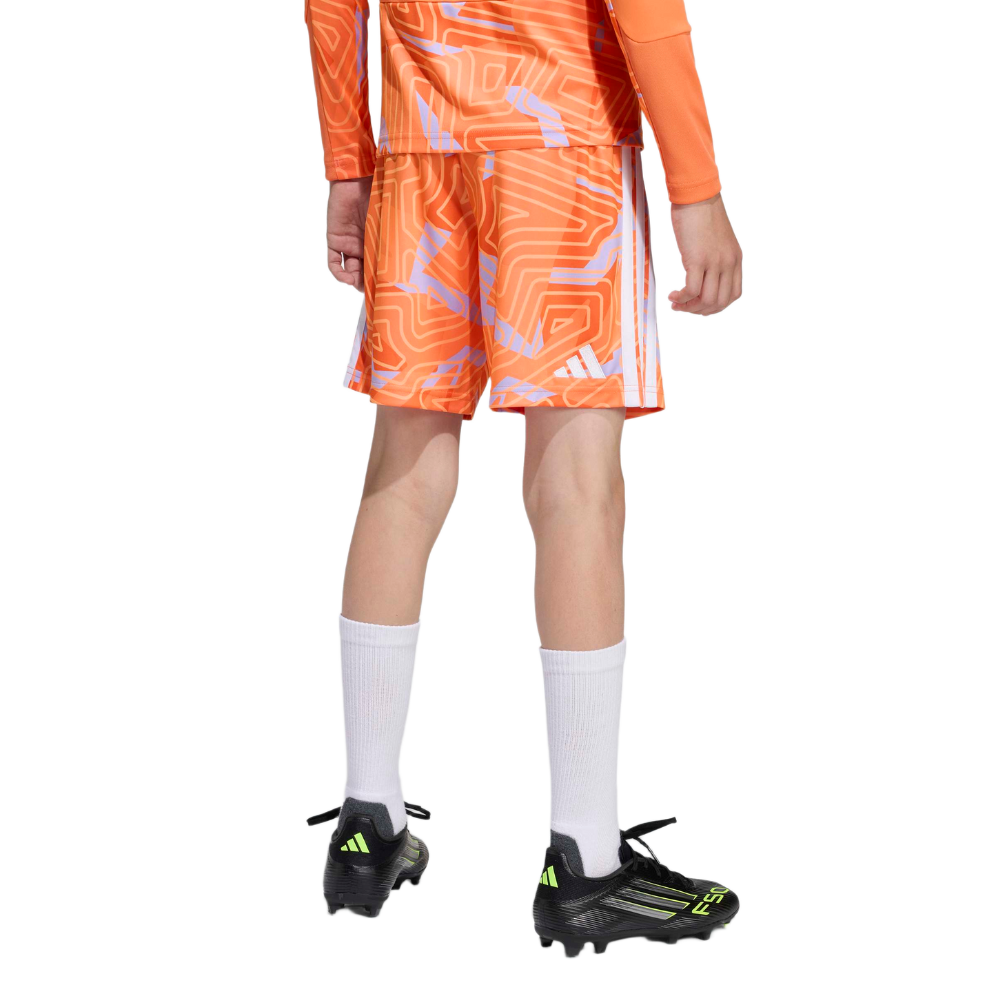 Rear view of a person wearing orange patterned soccer shorts and jersey, high white socks, and black soccer cleats against a plain white background.