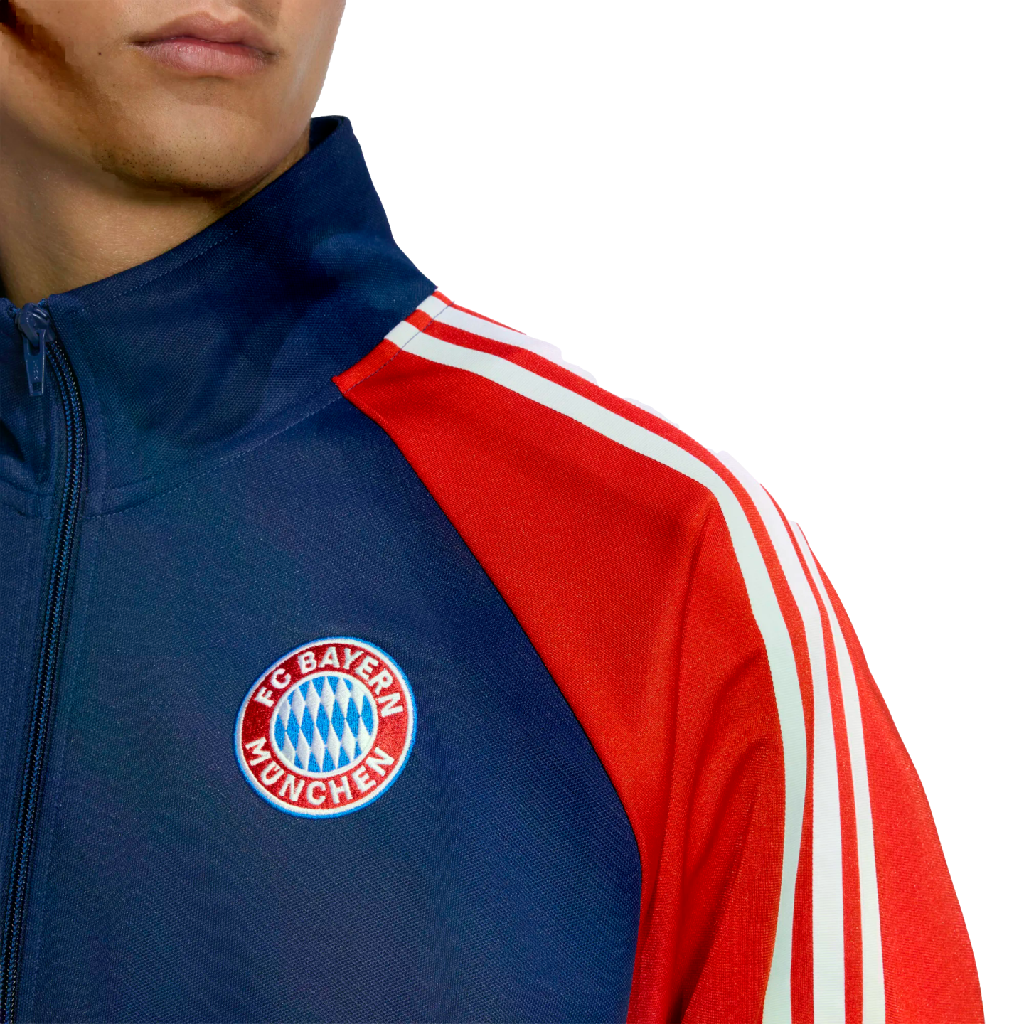 A person wears a navy blue and red FC Bayern München track jacket with the club's crest on the chest and white stripes on the sleeves.