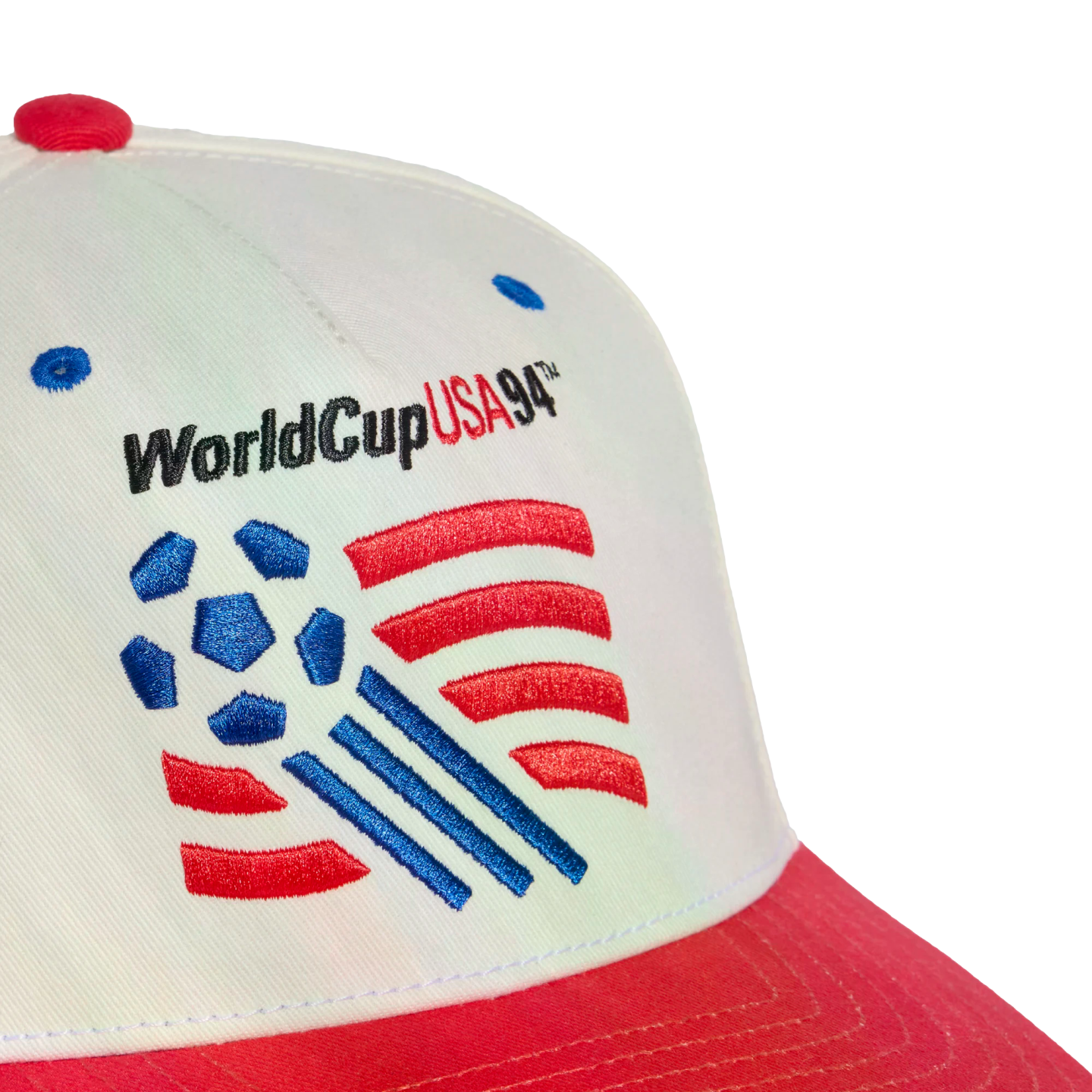 A close-up shot of a white baseball cap with a red brim featuring an embroidered logo for the 1994 FIFA World Cup. The logo includes the text "WorldCupUSA94™" above a graphic of a blue soccer ball with red stripes and blue motion lines.