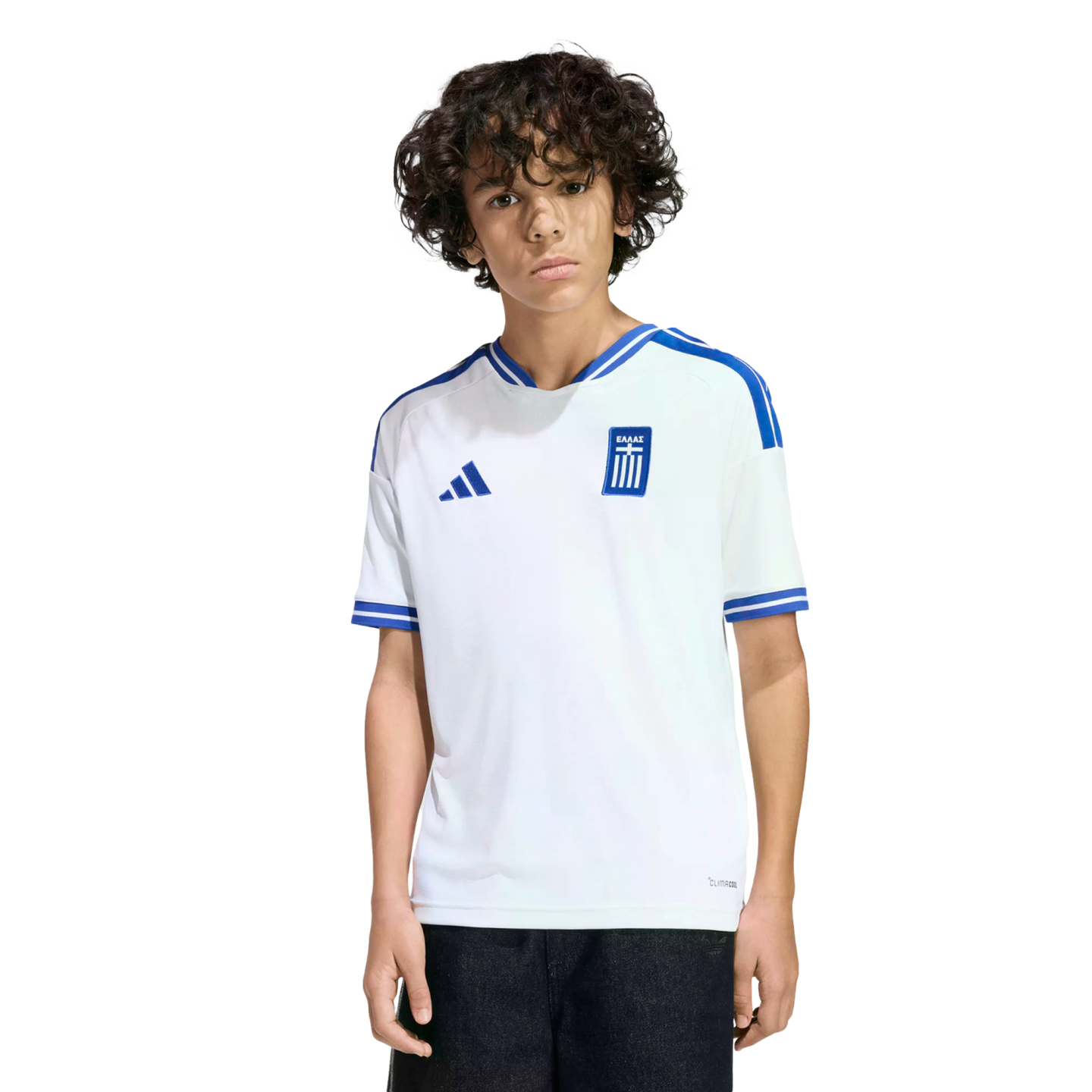 A young person with curly dark hair wearing a white Greece national team soccer jersey with blue accents, standing against a solid black background.
