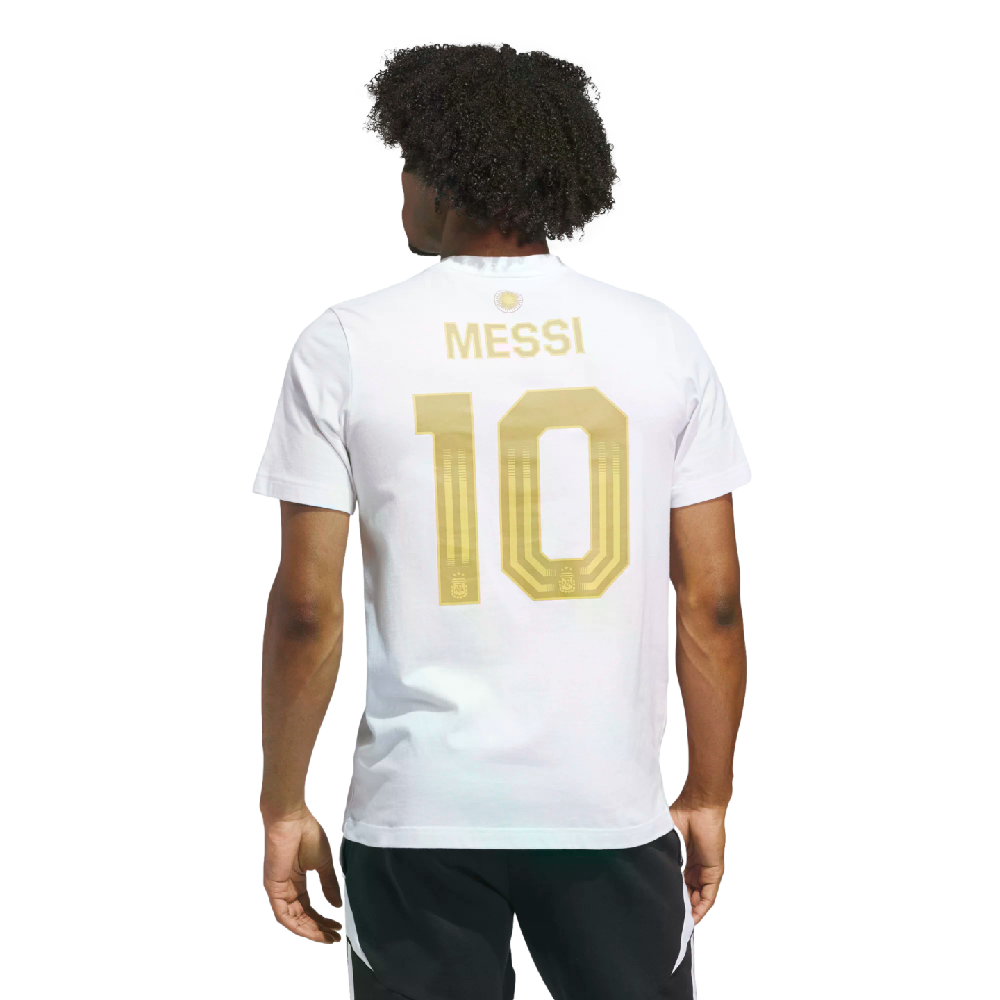 Rear view of a man in a white T-shirt featuring gold "MESSI 10" lettering on the back. He has dark curly hair and wears black athletic shorts against a black background.