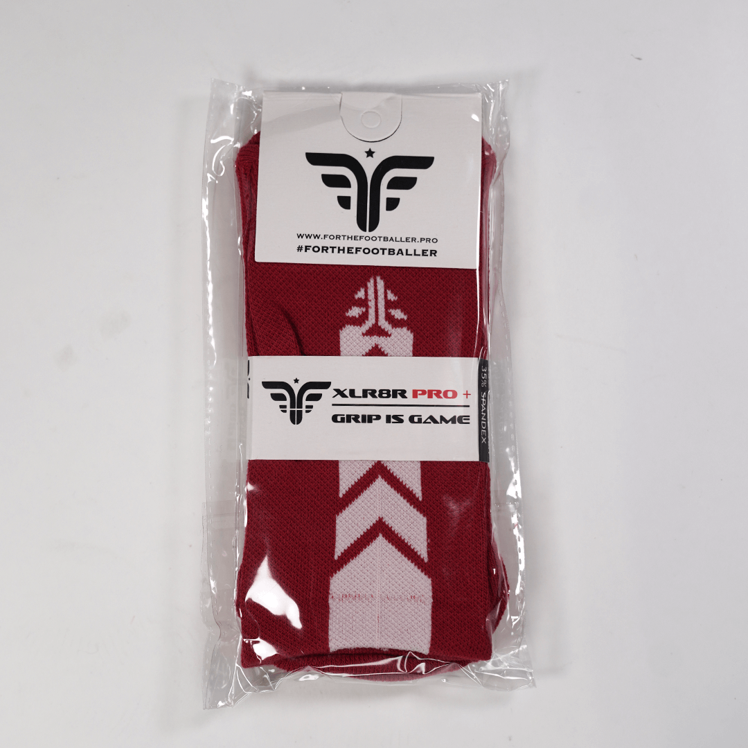 A pair of For The Footballer XLR8R Pro No Slip Socks in red, featuring white chevron patterns and displayed in clear plastic packaging with branded white labels.