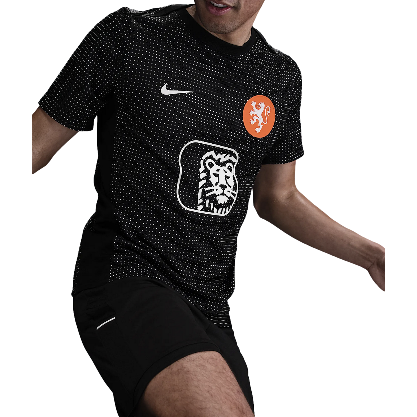 Man in a black Nike Netherlands training jersey with white dots and lion logos, captured in an athletic pose.