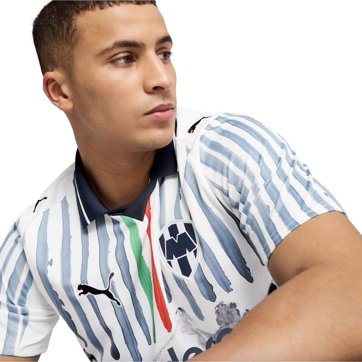 Close-up of a man looking away, wearing a white soccer jersey with blue painted stripes, a Puma logo, and a CF Monterrey crest.