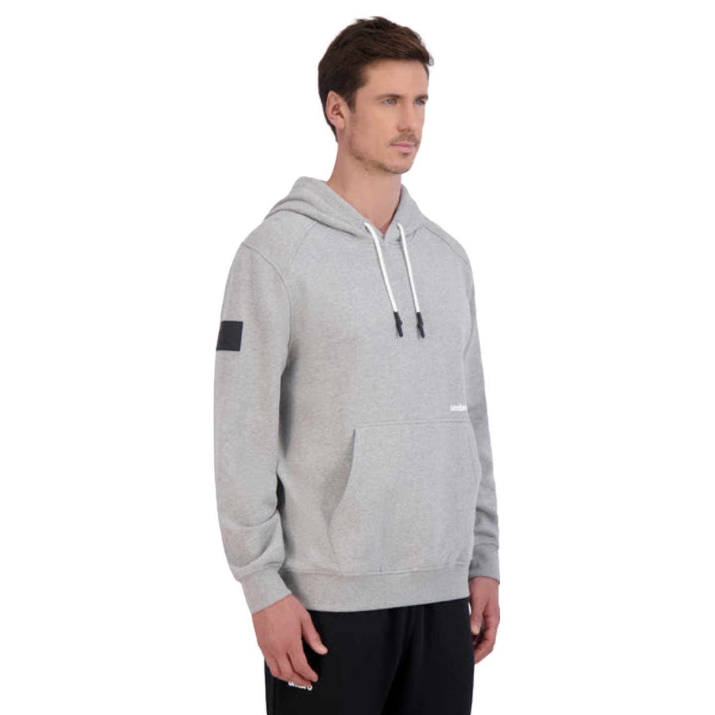 Man wearing a grey hoodie with white drawstrings and black sweatpants, standing against a plain black background.