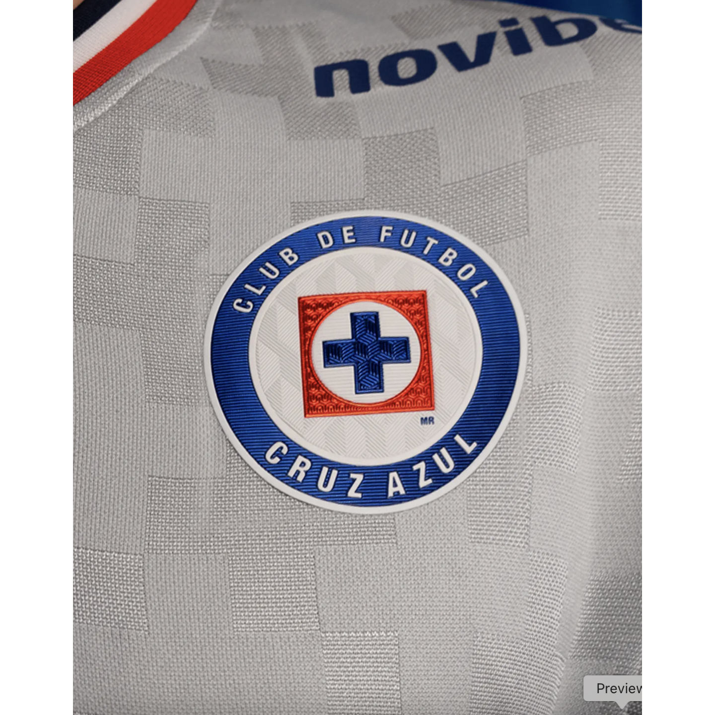 Close-up of the Club de Futbol Cruz Azul circular crest on a grey textured soccer jersey.