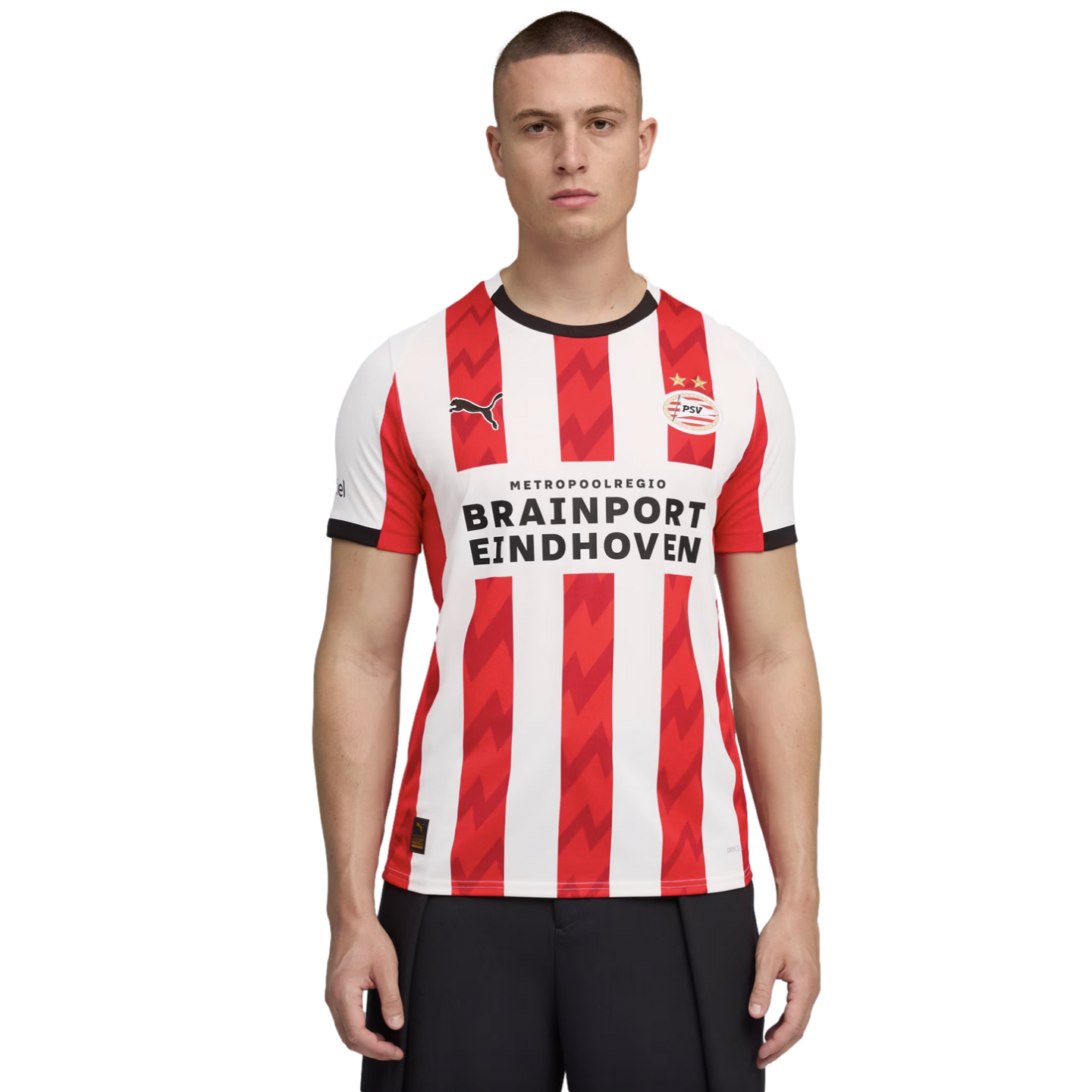 A man models a red and white striped PSV Eindhoven Puma soccer jersey featuring the "Brainport Eindhoven" sponsor logo on a solid black background.