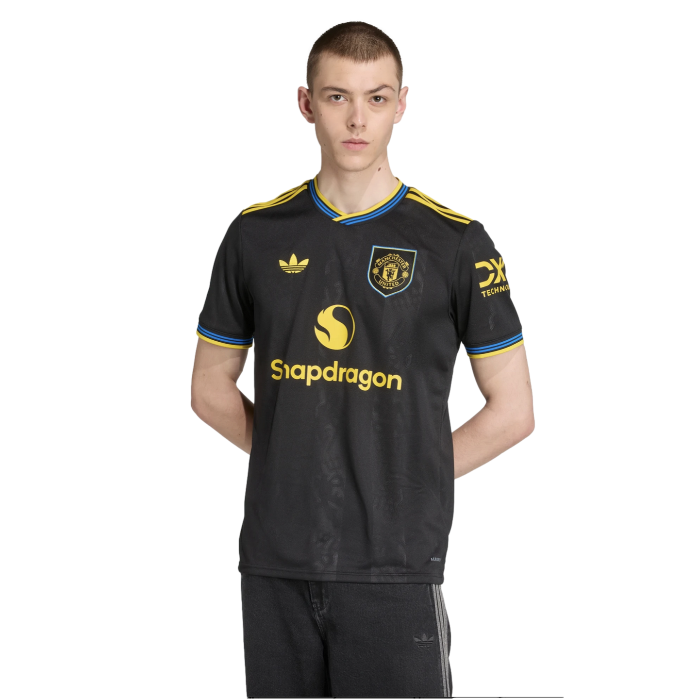 A man wearing a black Manchester United soccer jersey with yellow and blue accents and the Snapdragon logo, against a black background.