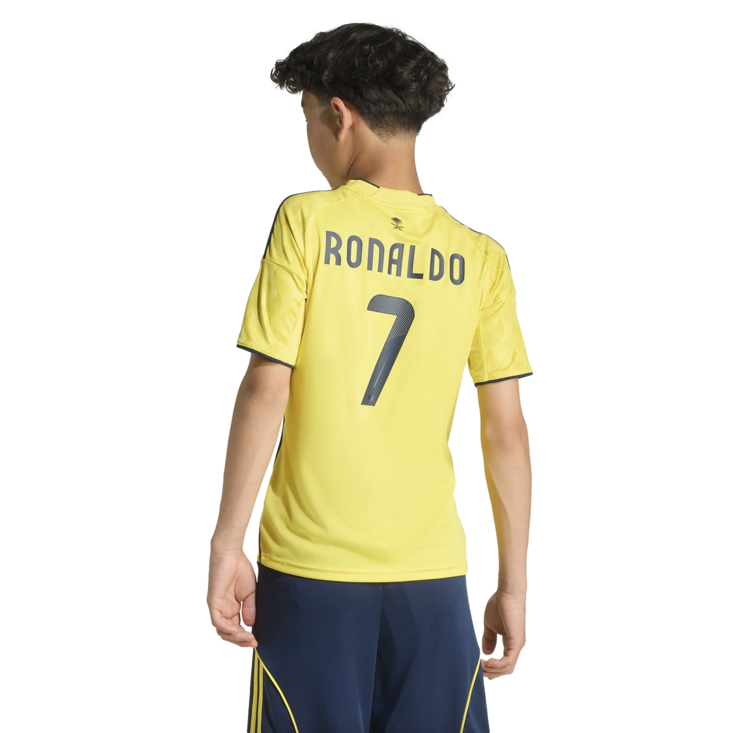 Back view of a boy in a yellow "RONALDO 7" soccer jersey and navy shorts against a black background.