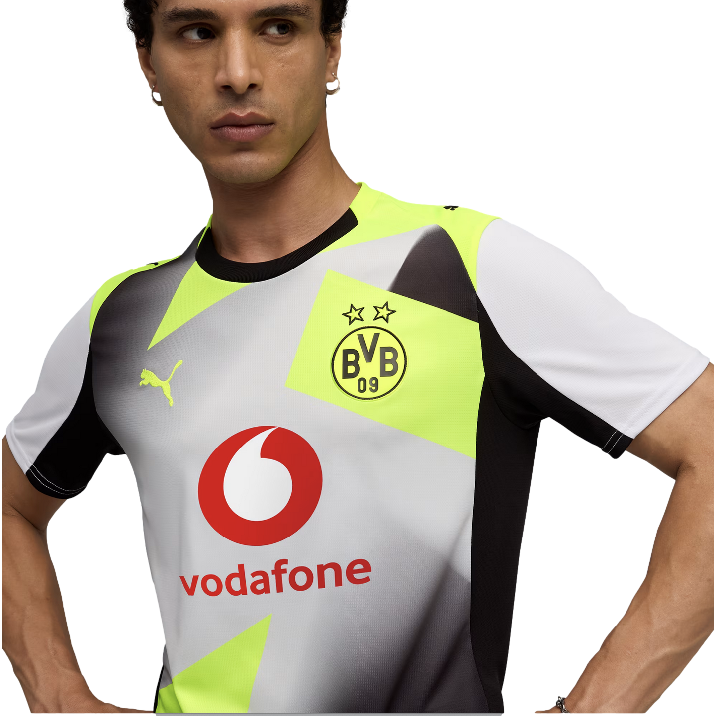 A man wearing a white, grey, and neon yellow Borussia Dortmund soccer jersey featuring a Vodafone sponsor logo, Puma branding, and geometric patterns.