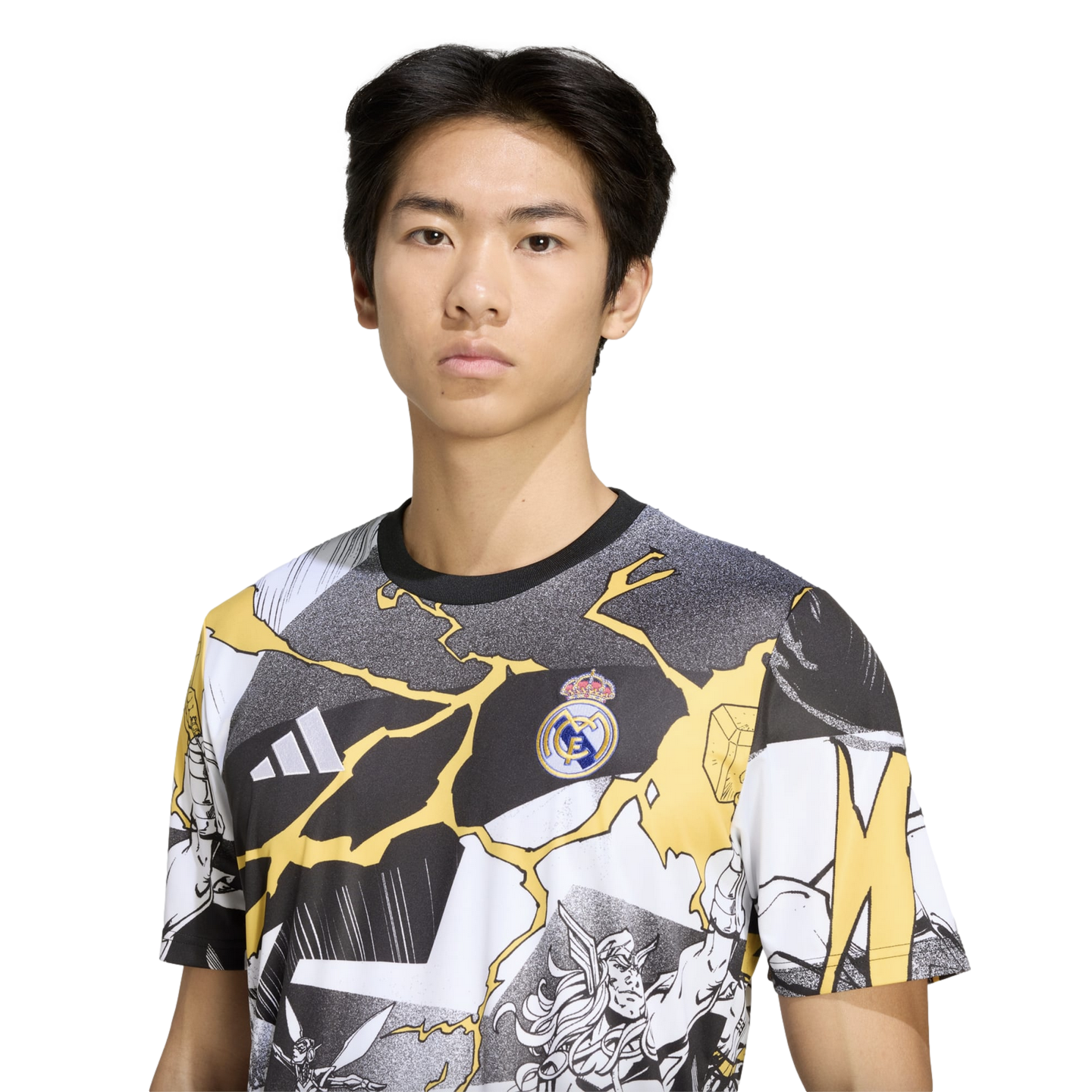 A young man wearing a Real Madrid t-shirt featuring comic-style graphics and yellow lightning bolts against a solid black background.