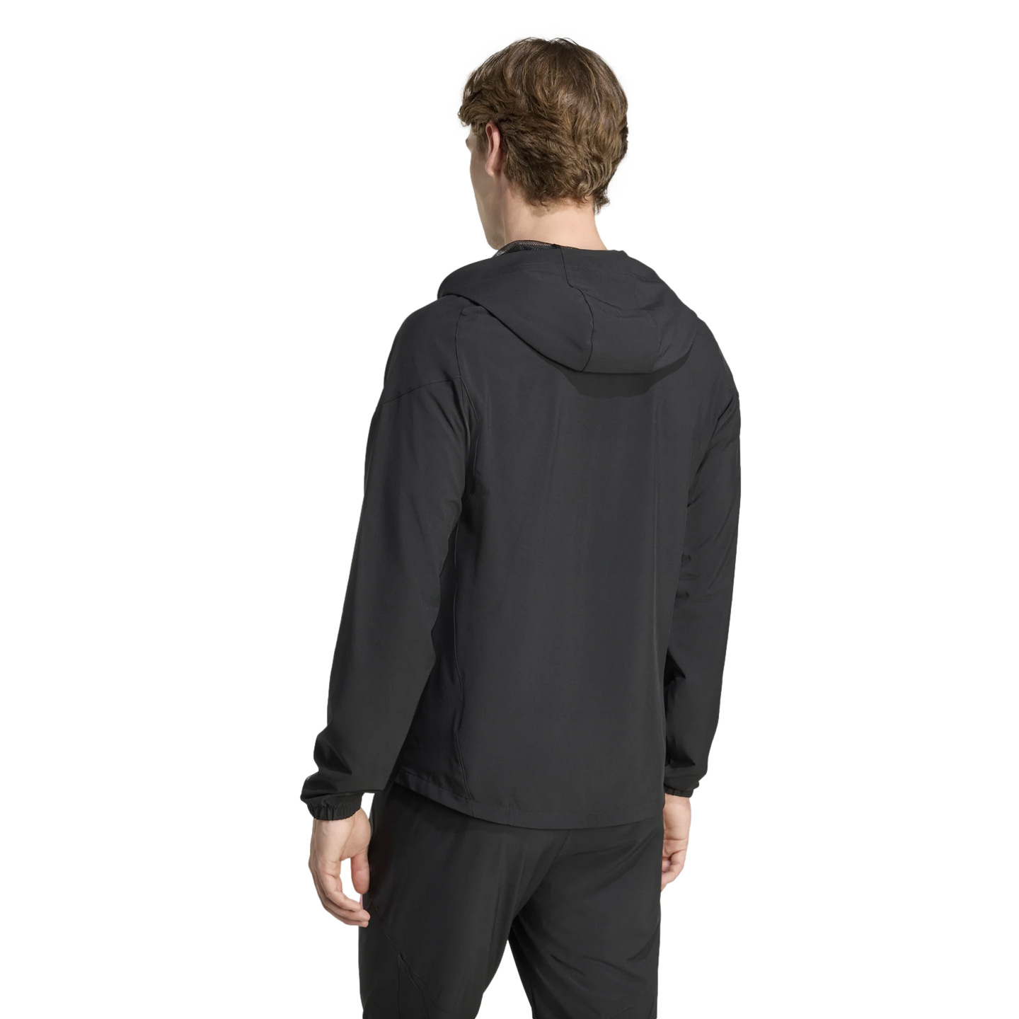 Rear view of a person wearing a black hooded athletic jacket and matching pants against a plain black background.