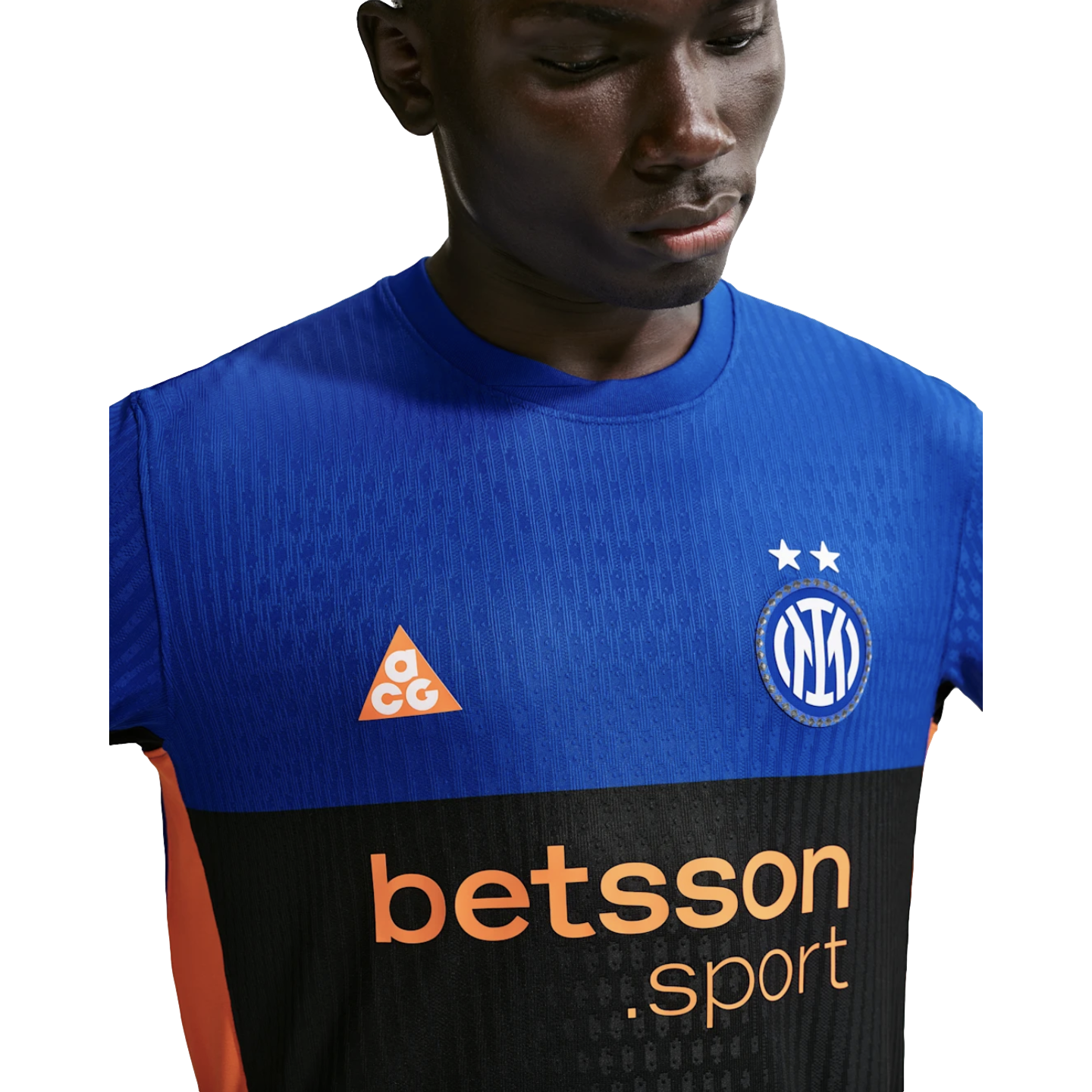 A man wearing a blue and black Inter Milan soccer jersey with orange ACG and Betsson Sport logos against a black background.