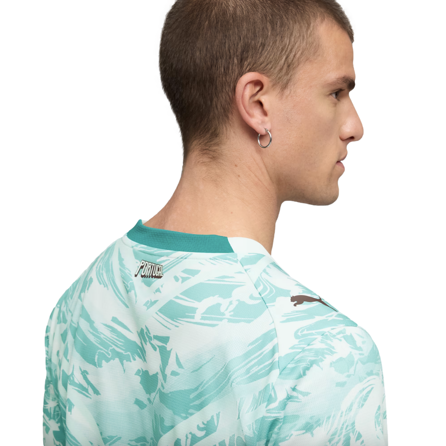 A back and side profile of a man with short hair wearing a white and teal abstract-patterned t-shirt. The shirt features a solid teal collar, the word "PORTUGAL" on the upper back, and a small Puma logo on the shoulder.