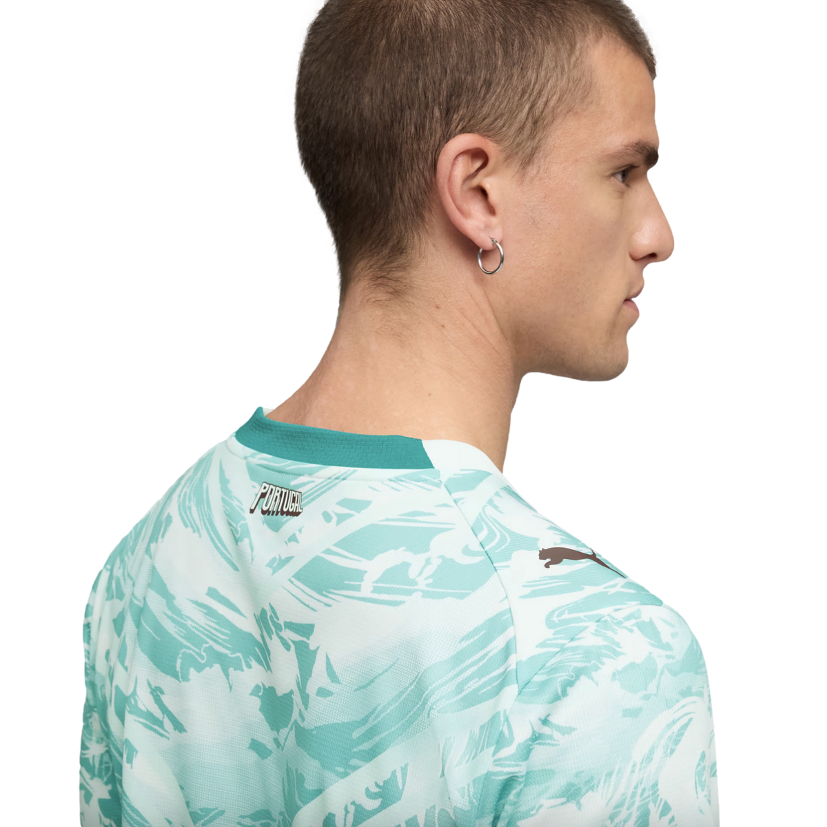 A back and side profile of a man with short hair wearing a white and teal abstract-patterned t-shirt. The shirt features a solid teal collar, the word "PORTUGAL" on the upper back, and a small Puma logo on the shoulder.