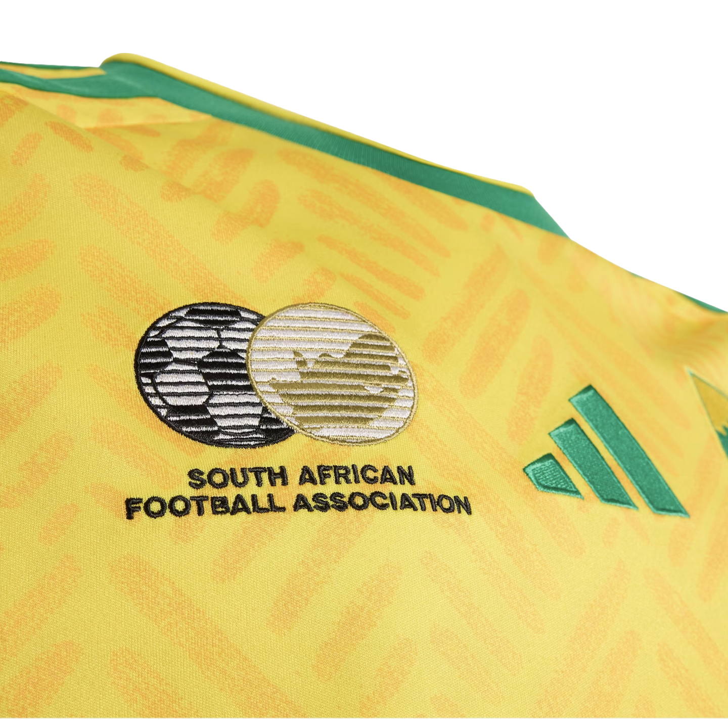 Close-up of a yellow South Africa soccer jersey featuring the embroidered South African Football Association crest and green Adidas logo.