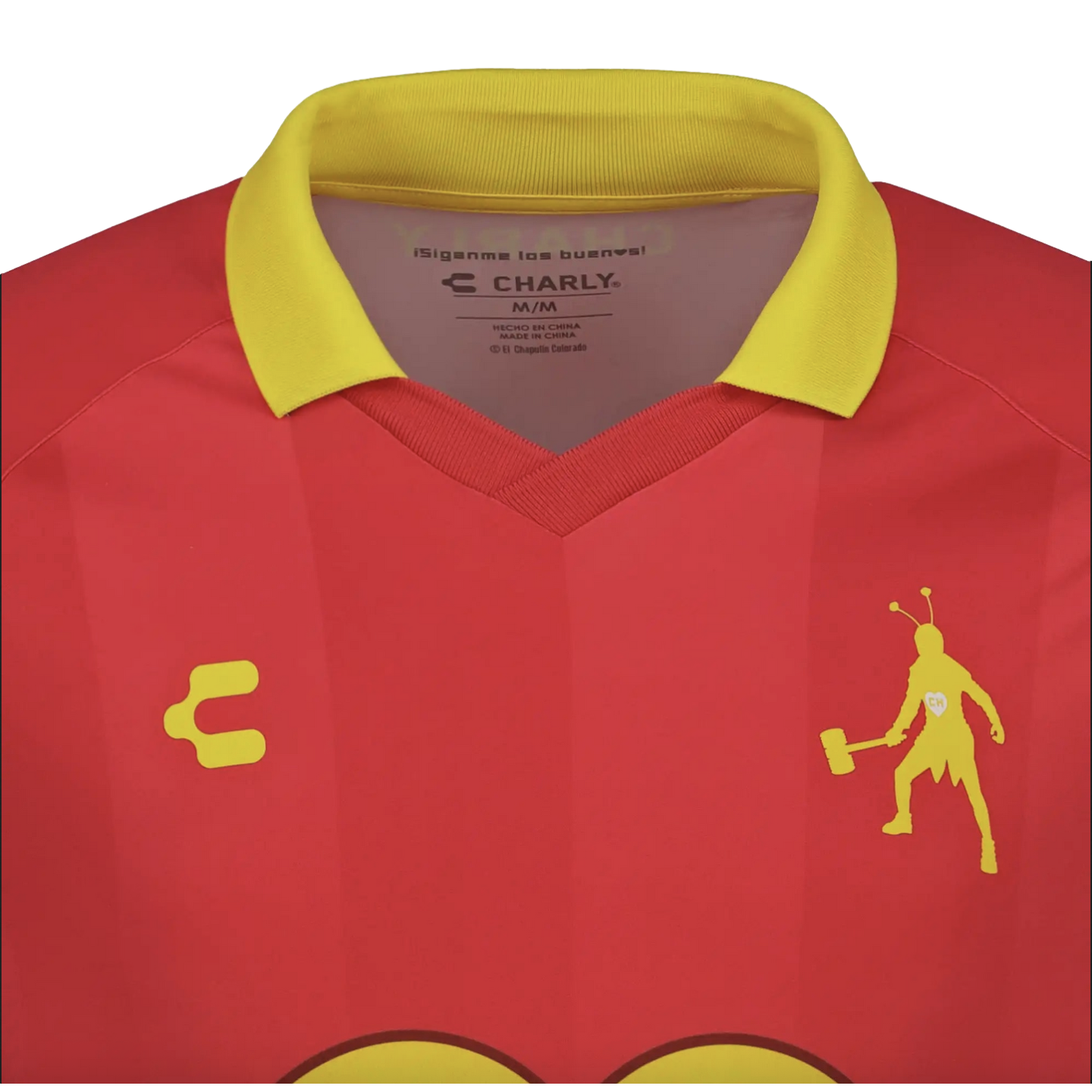 Close-up of a red soccer jersey with a yellow collar. It features a yellow silhouette of El Chapulín Colorado holding a mallet and the Charly brand logo on the chest.