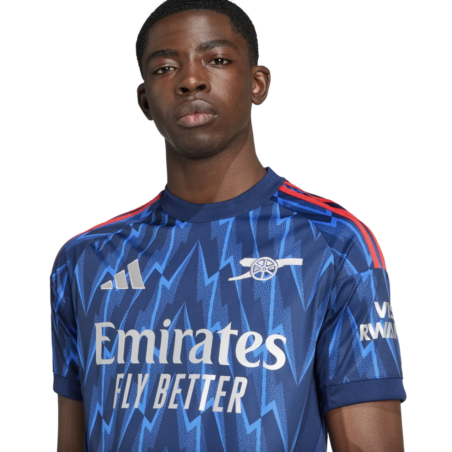 Portrait of a young Black man wearing a blue Arsenal football jersey with a zigzag pattern, posed against a black background.