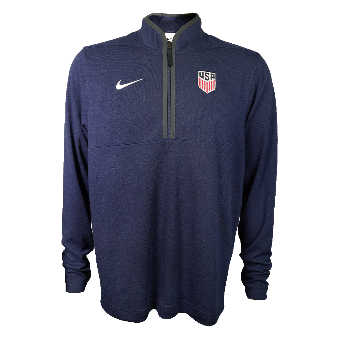 Dark blue long-sleeve Nike quarter-zip pullover with a white swoosh and USA Soccer crest, shown on a solid green background.