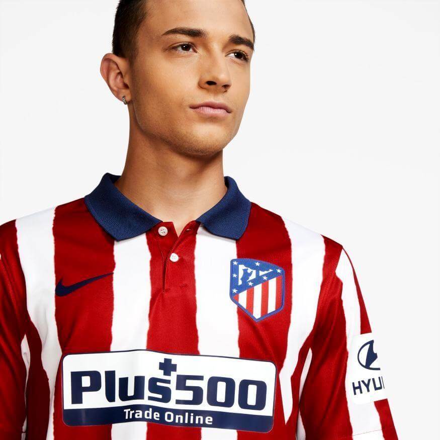 Young man in a red and white striped Atlético Madrid soccer jersey with a blue collar.